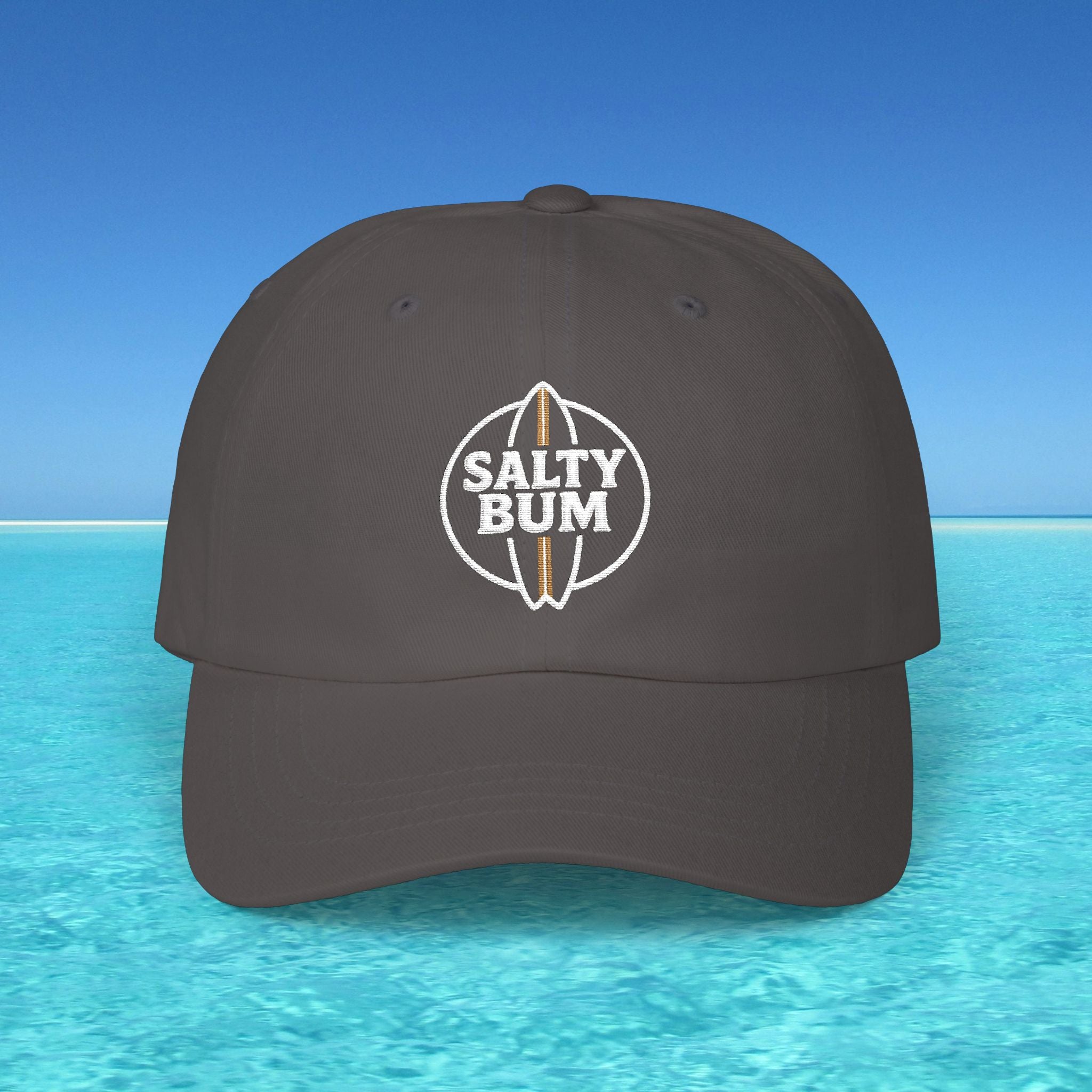 Dark gray cap with 'Salty Bum' logo on a blue water and sky background