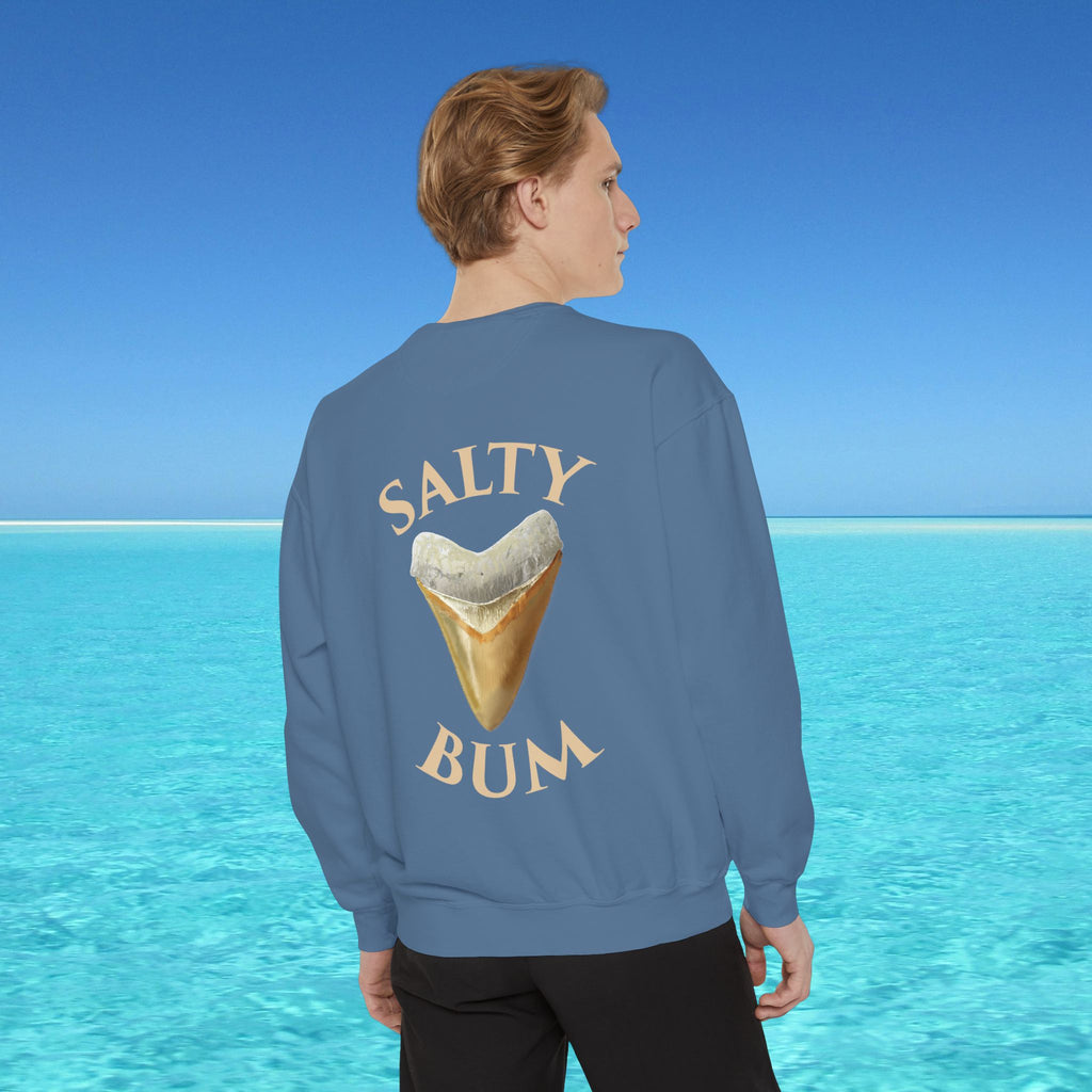Person wearing a blue sweatshirt with 'Salty Bum' text and ice cream cone graphic, standing in front of a clear blue ocean.