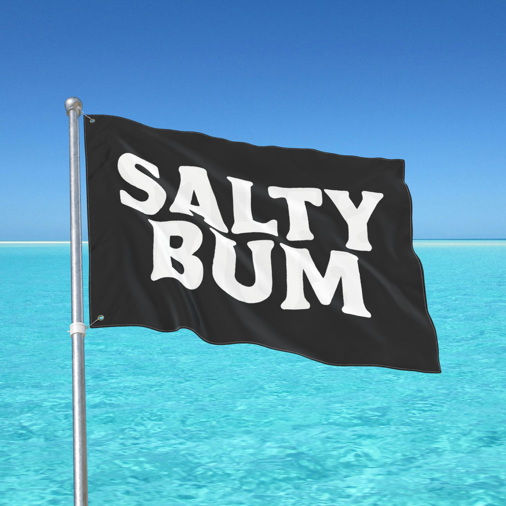 Black flag with 'Salty Bum' text against a clear blue sky and ocean.