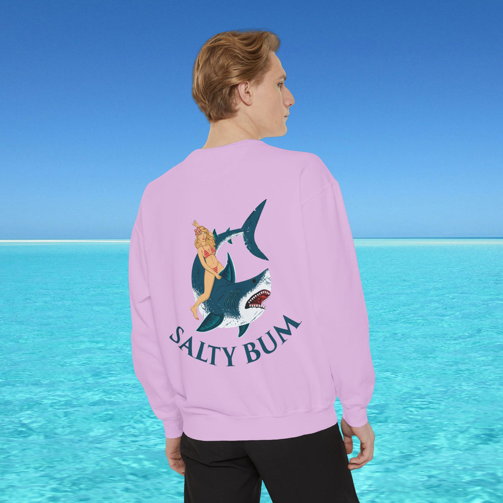 Person wearing a pink sweatshirt with a shark and bikini graphic and 'Salty Bum' text, standing in front of a blue ocean.