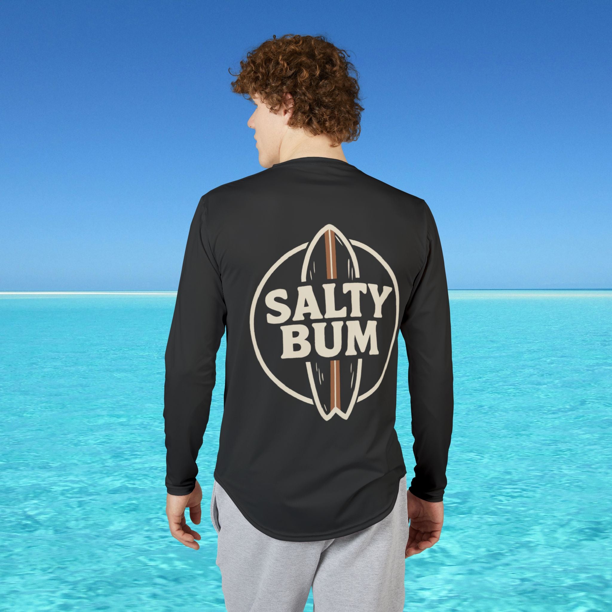 Person wearing a black long-sleeve shirt with 'Salty Bum' logo in a beach setting