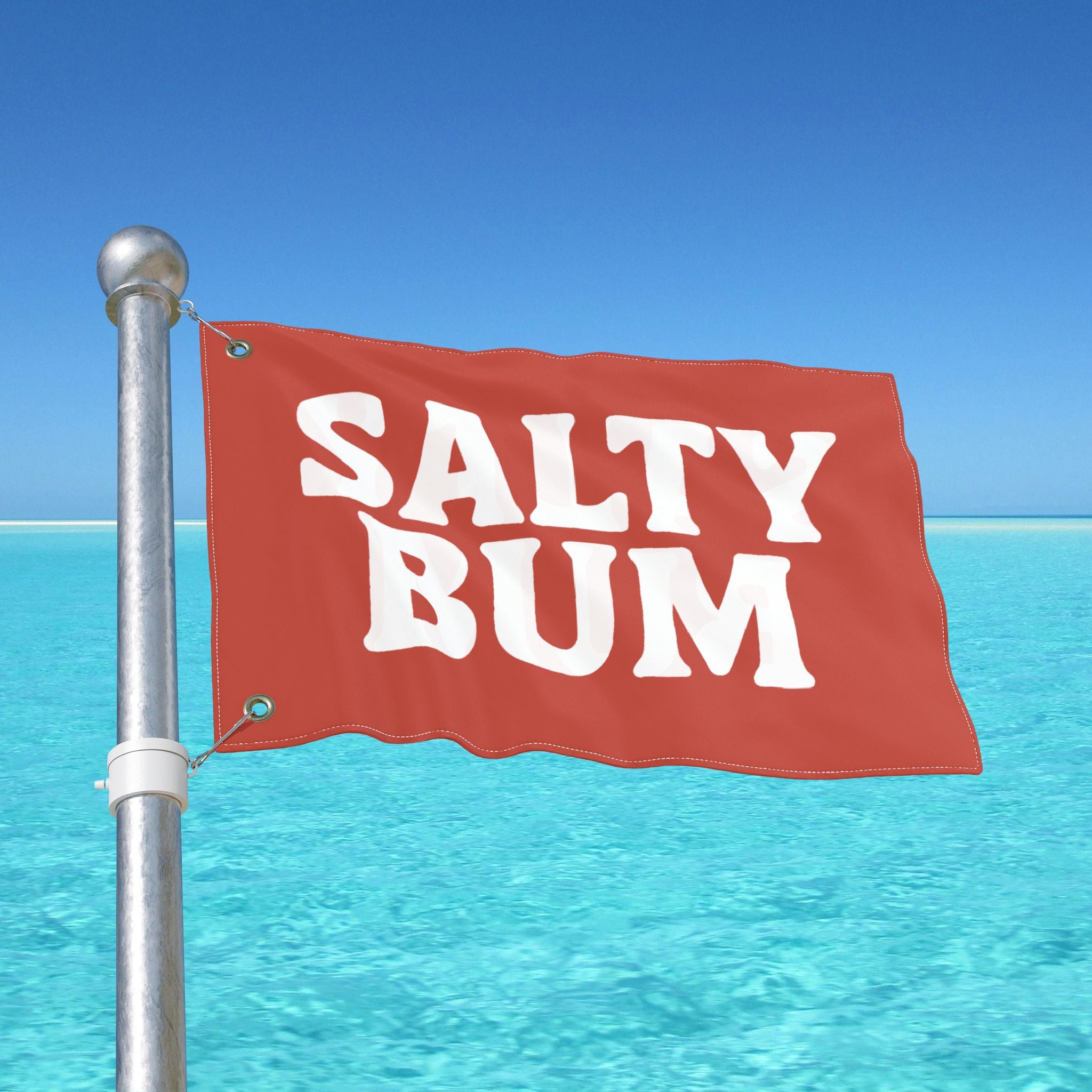 Red flag with 'Salty Bum' text against a clear blue sky and ocean.