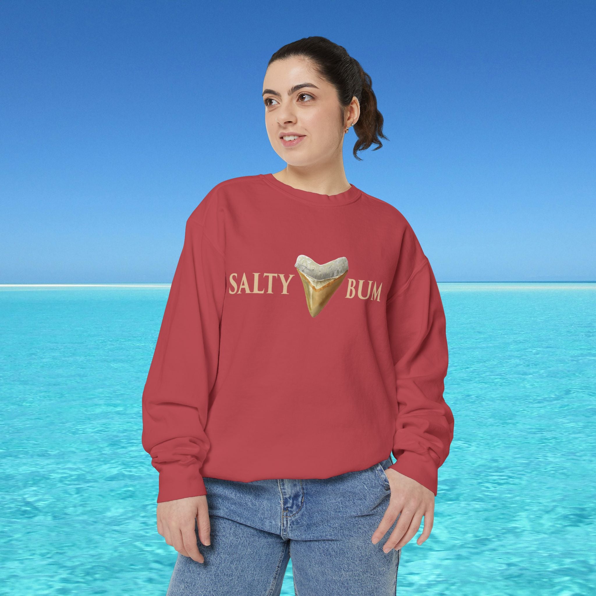 Person wearing a red sweatshirt with 'Salty Bum' text and ice cream graphic against a blue water and sky background