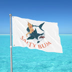 Flag with a graphic design of a woman on a shark and 'Salty Bum' text against a blue sky and ocean background.