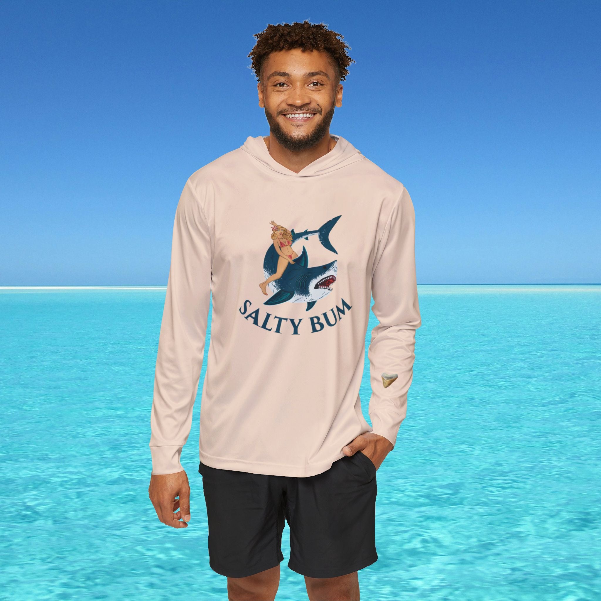 Man wearing a 'Salty Bum' hoodie with a shark graphic against a clear blue ocean background