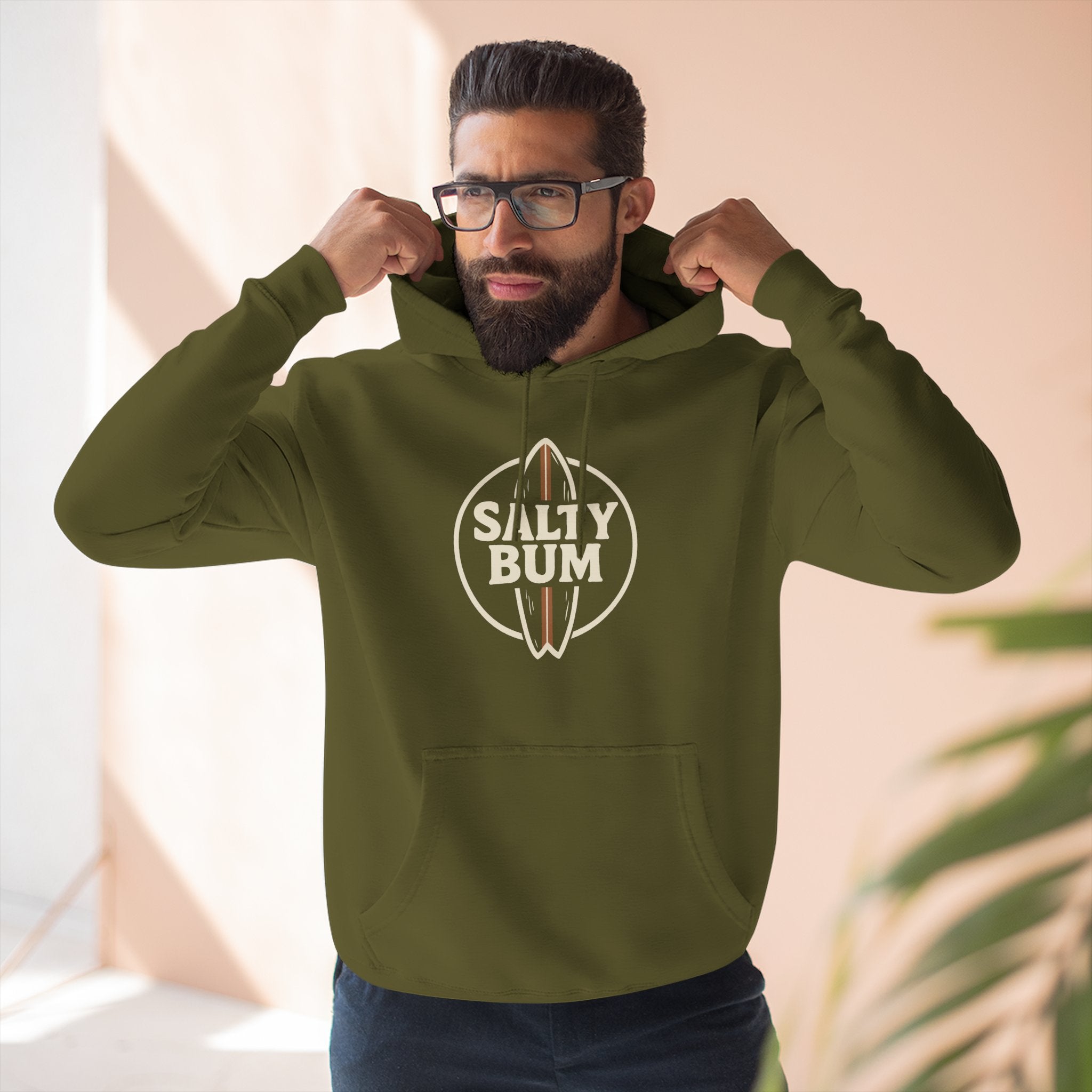 Man wearing a green hoodie with 'Salty Bum' logo indoors