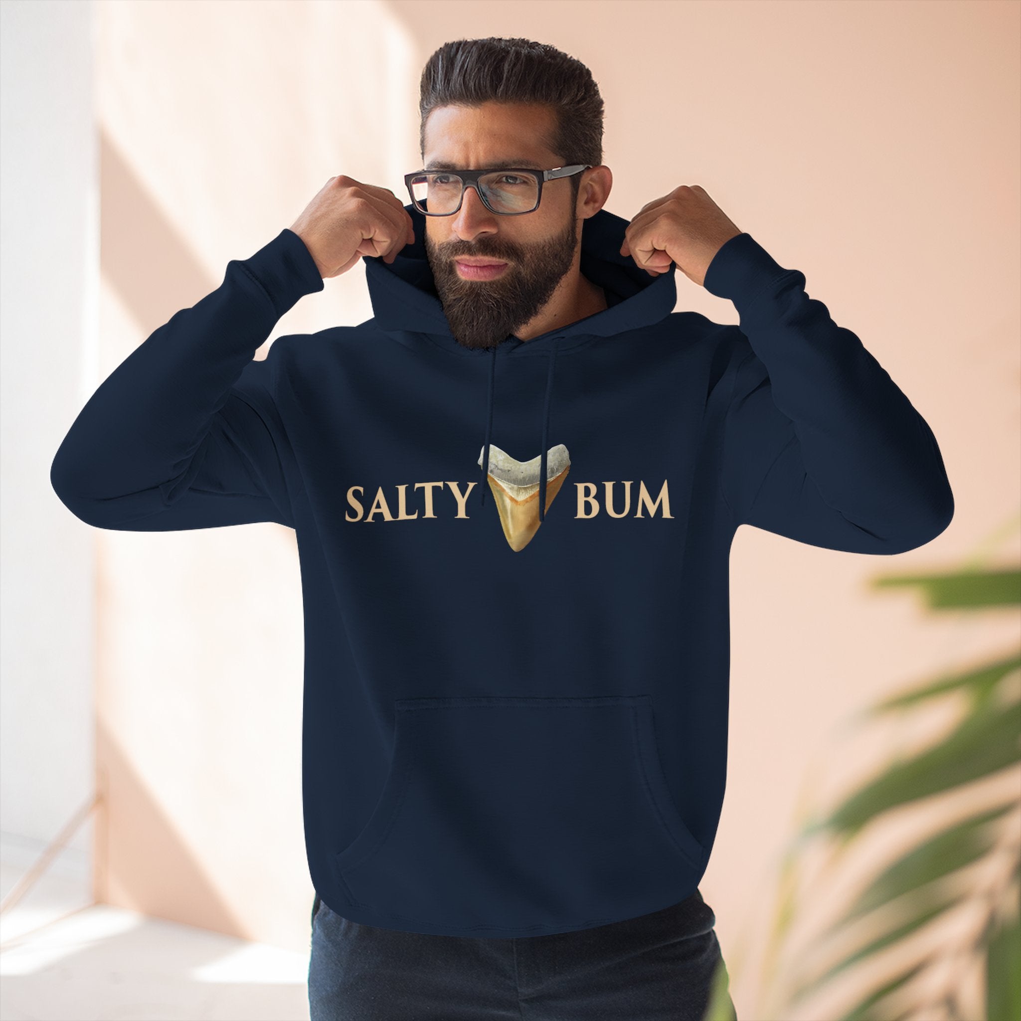 Man wearing a navy hoodie with 'Salty Bum' text and graphic, indoors.