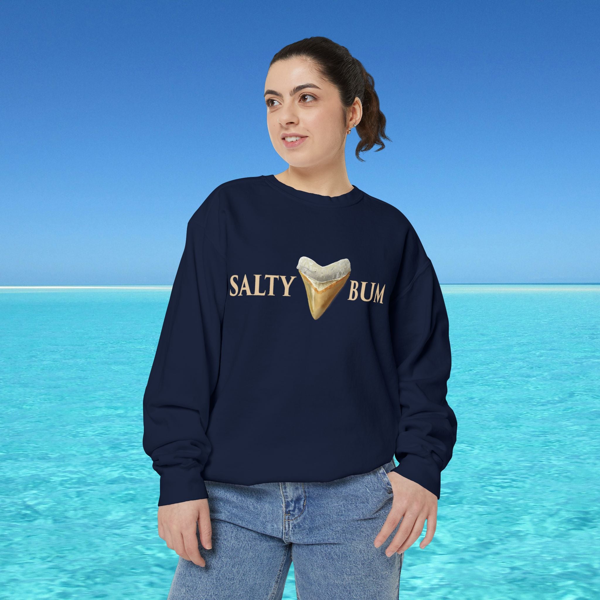 Person wearing a navy sweatshirt with 'Salty Bum' text and ice cream graphic against a blue ocean background