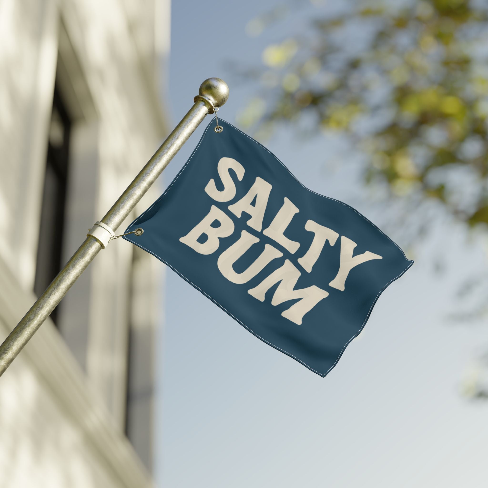 Flag with 'Salty Bum' text waving on a flagpole against a blurred background