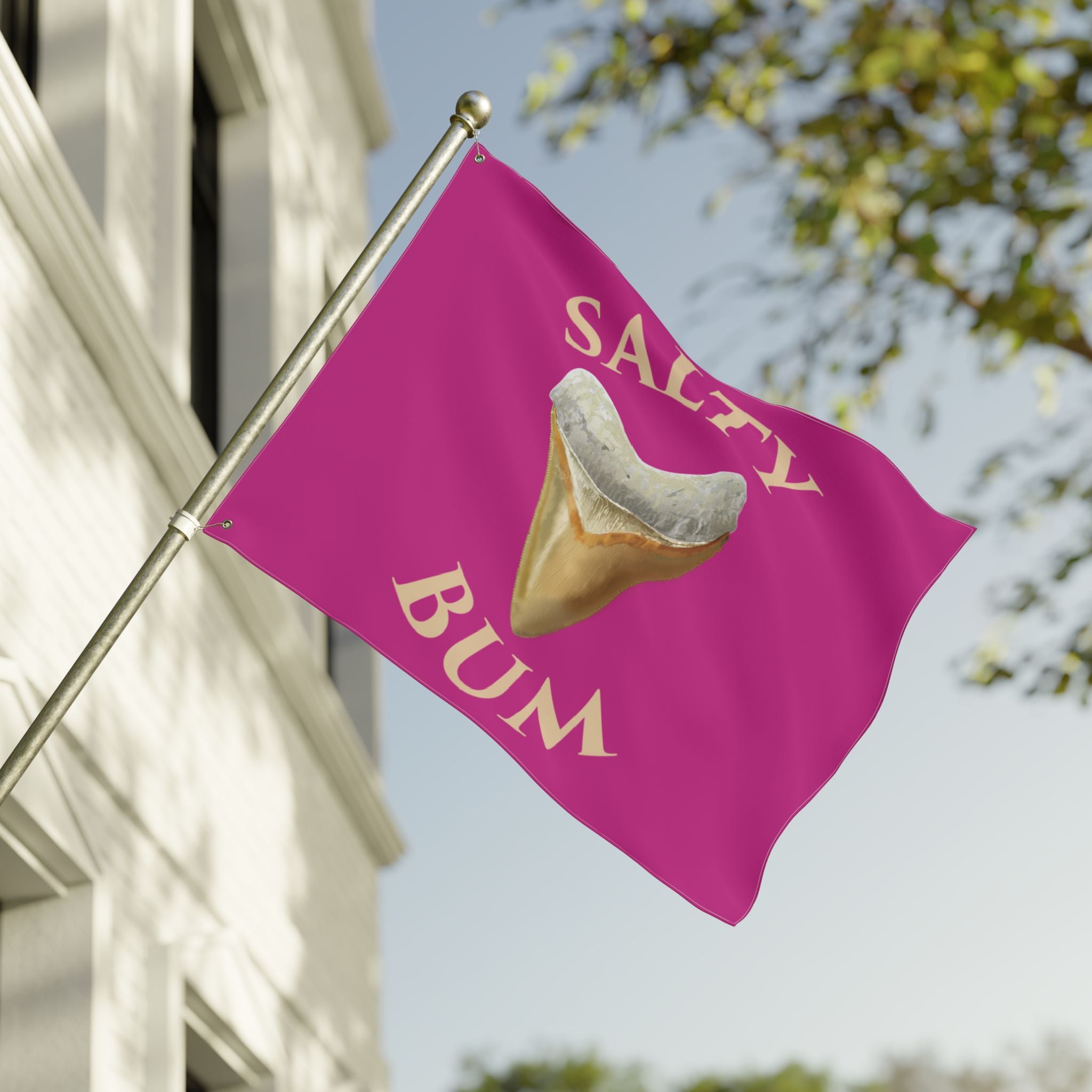 Flag with a corn dog graphic and 'Salty Bum' text on a pink background, waving in front of a building.