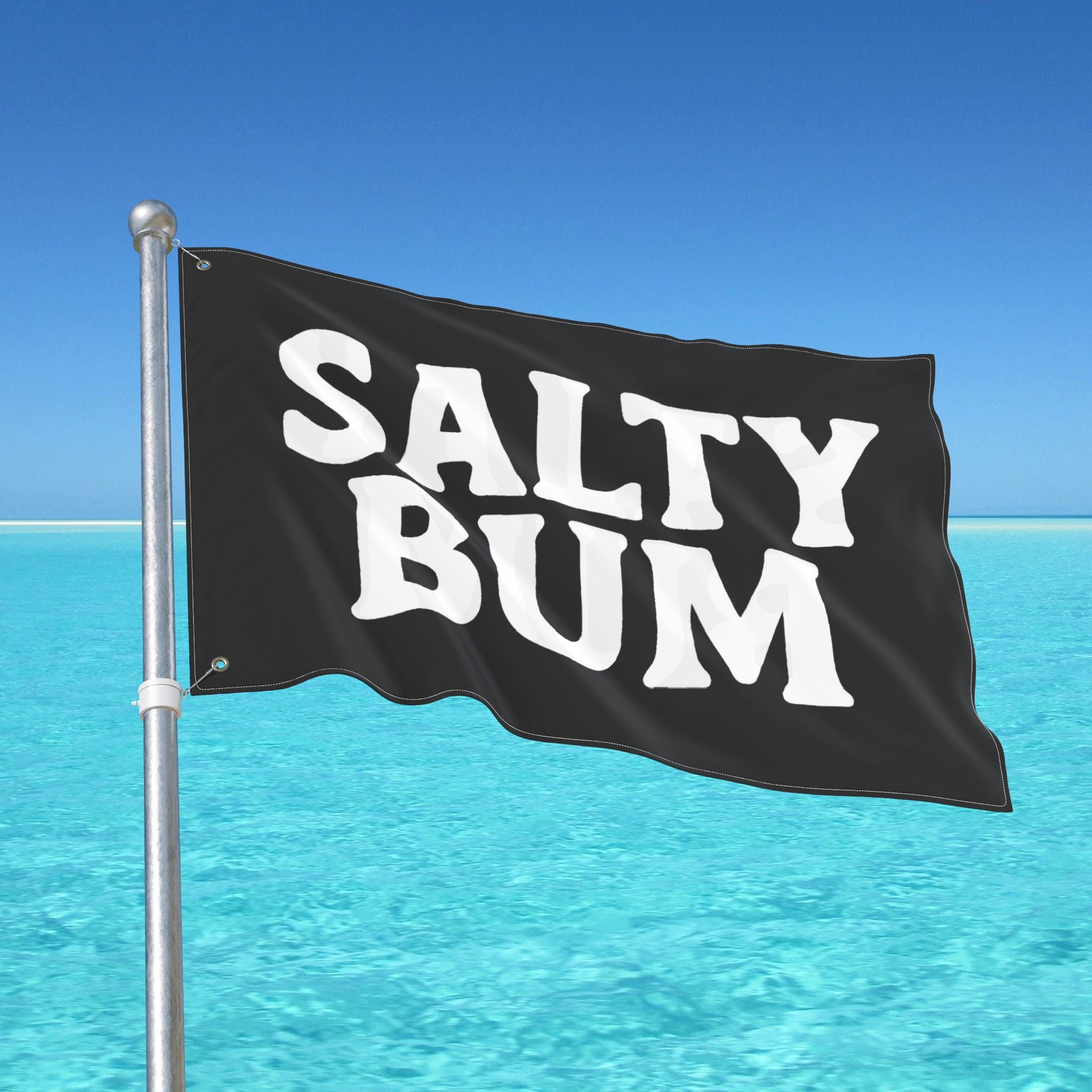 Flag with 'Salty Bum' text waving in front of a clear blue sky and ocean.