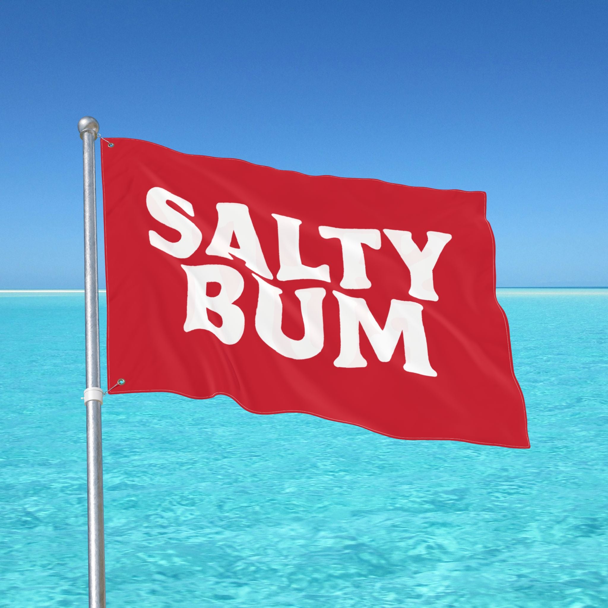 Red flag with 'Salty Bum' text against a clear blue sky and ocean.