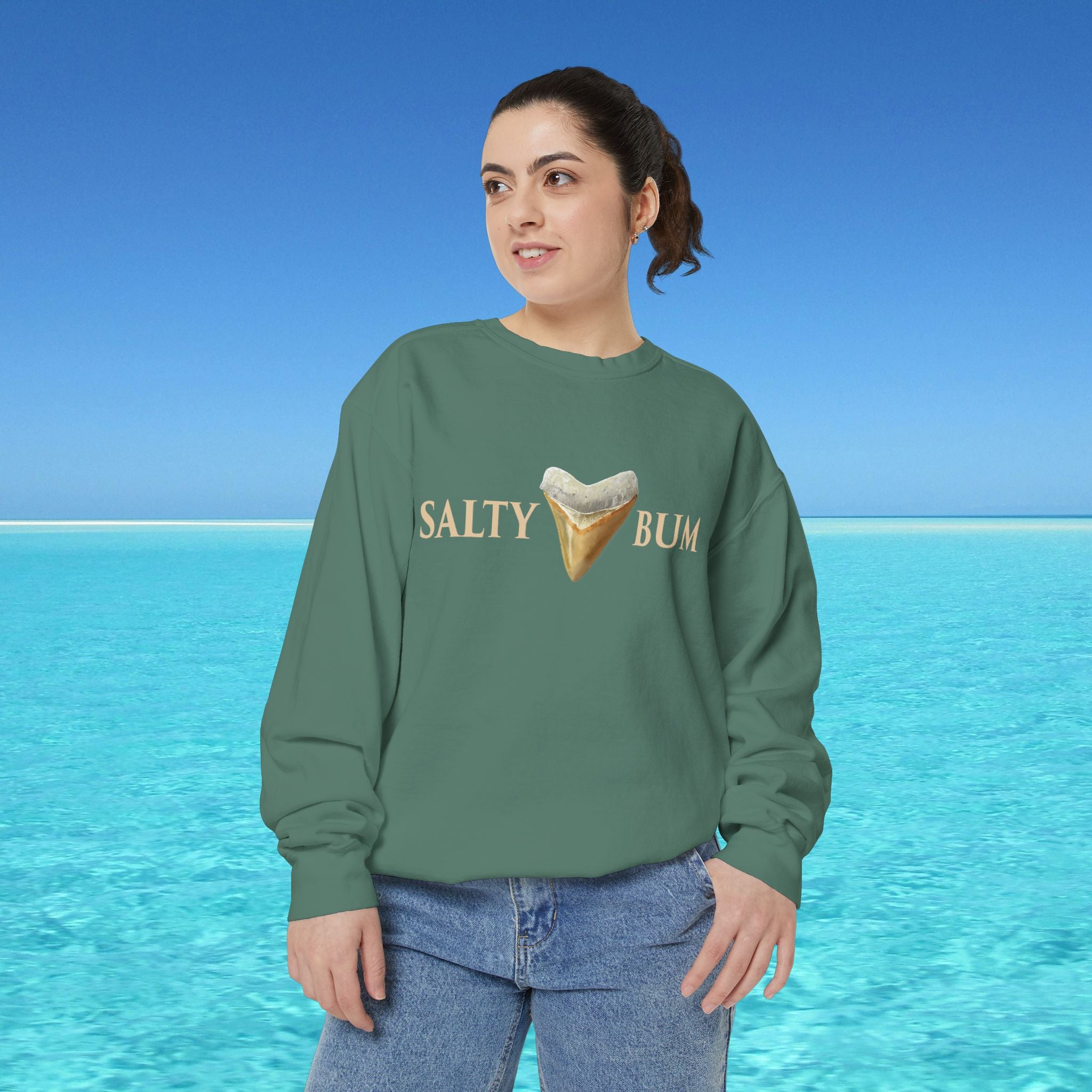 Person wearing a green sweatshirt with 'Salty Bum' text and ice cream graphic against a blue ocean background