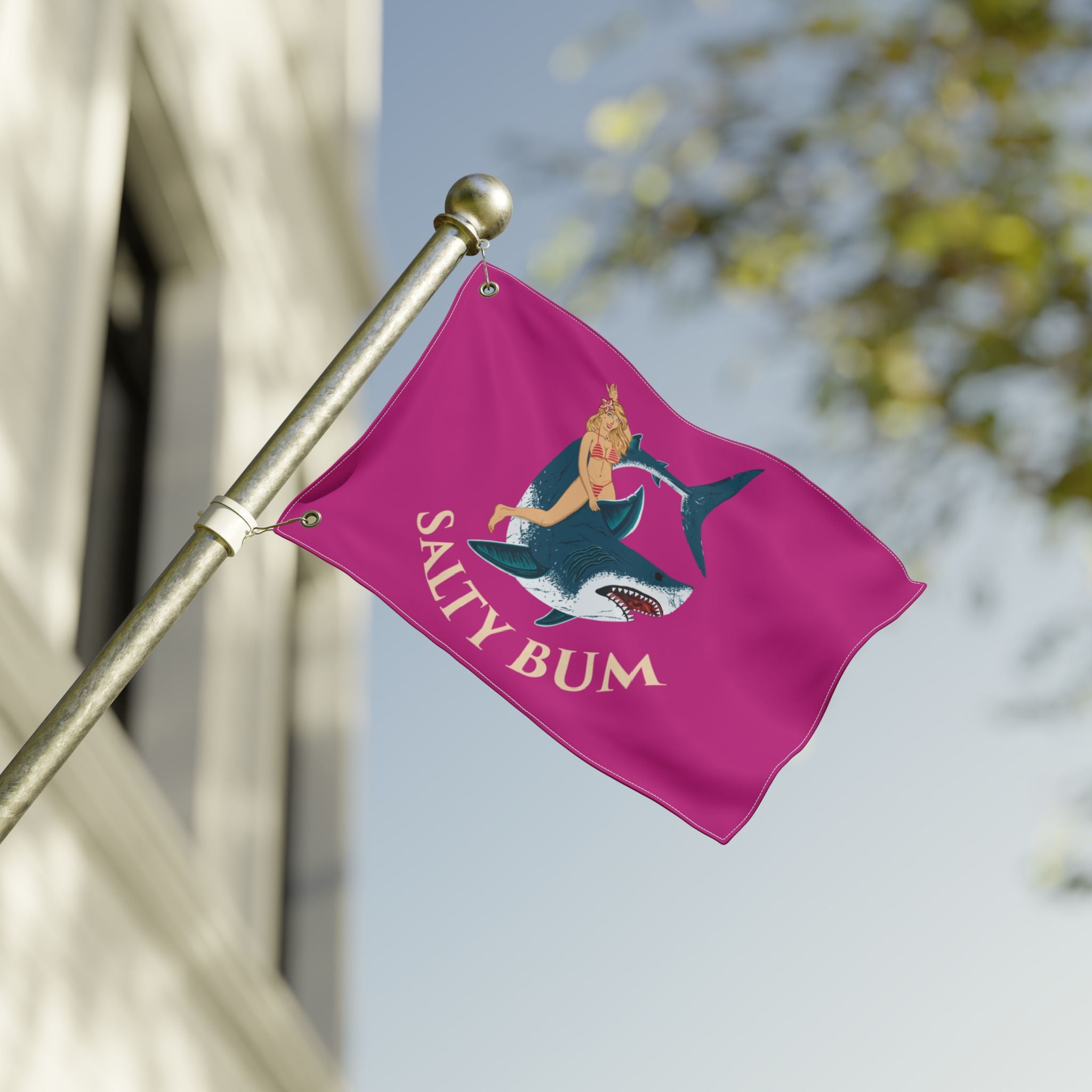 Pink flag with a graphic design and 'Salty Bum' text on a pole against a blurred background