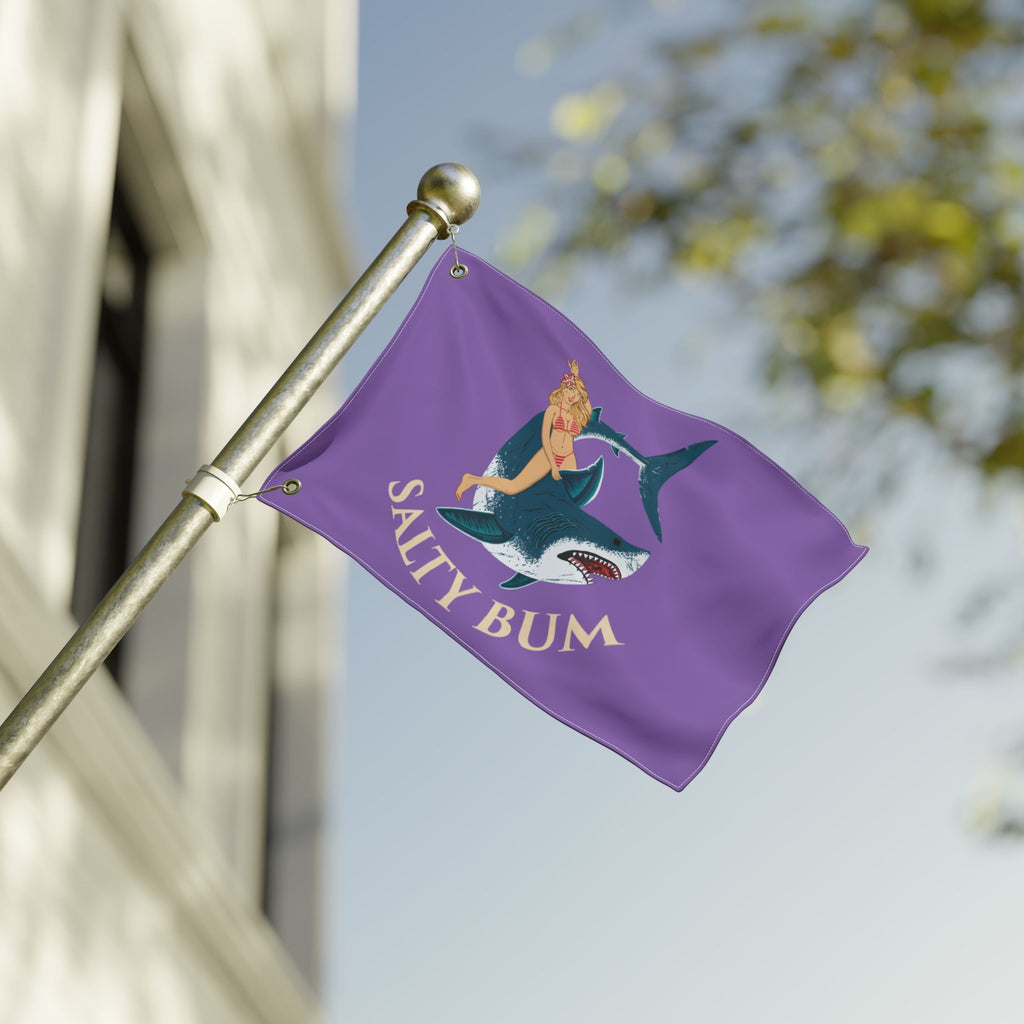 Purple flag with a graphic design and 'Salty Bum' text on a pole against a blurred background