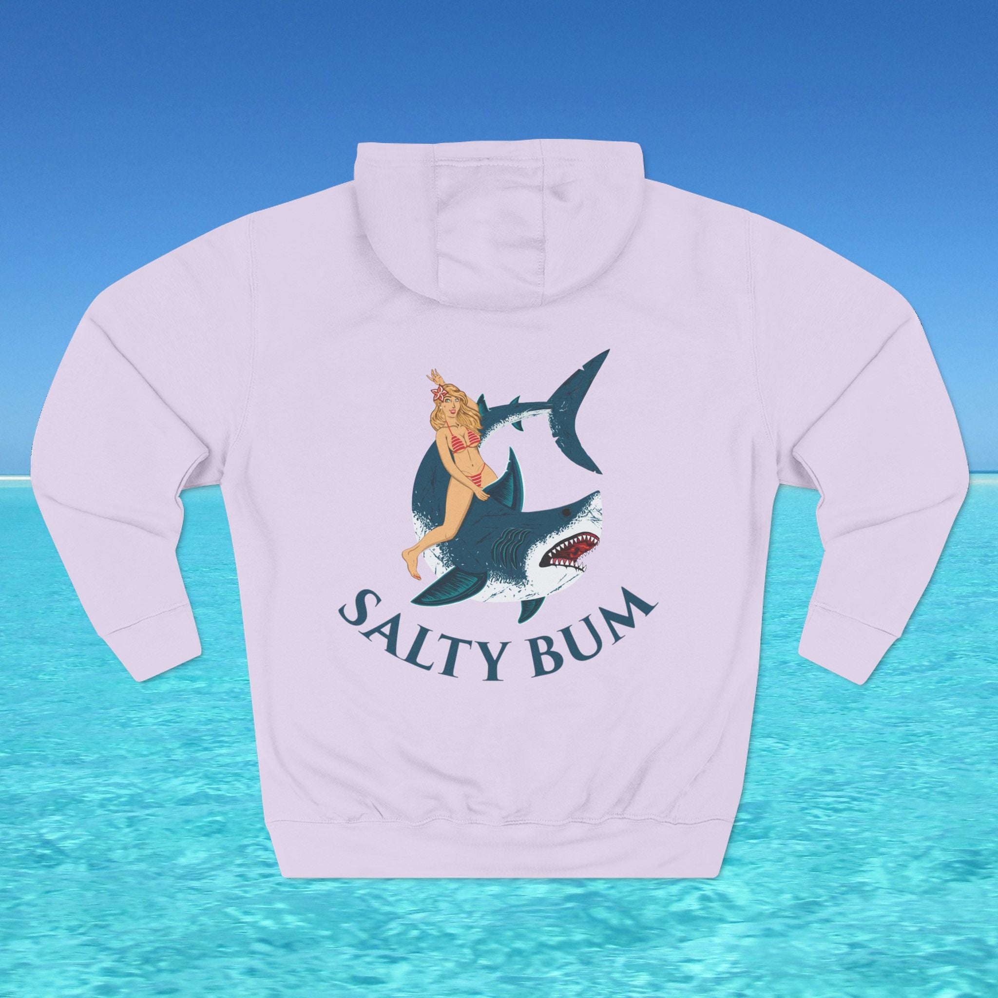 Light purple hoodie with a graphic of a woman on a shark and 'Salty Bum' text, against a blue water and sky background.