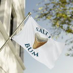 Flag with 'Salty Bum' logo featuring a shark tooth against a blurred outdoor background