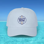 White cap with 'Salty Bum' logo on a blue water and sky background