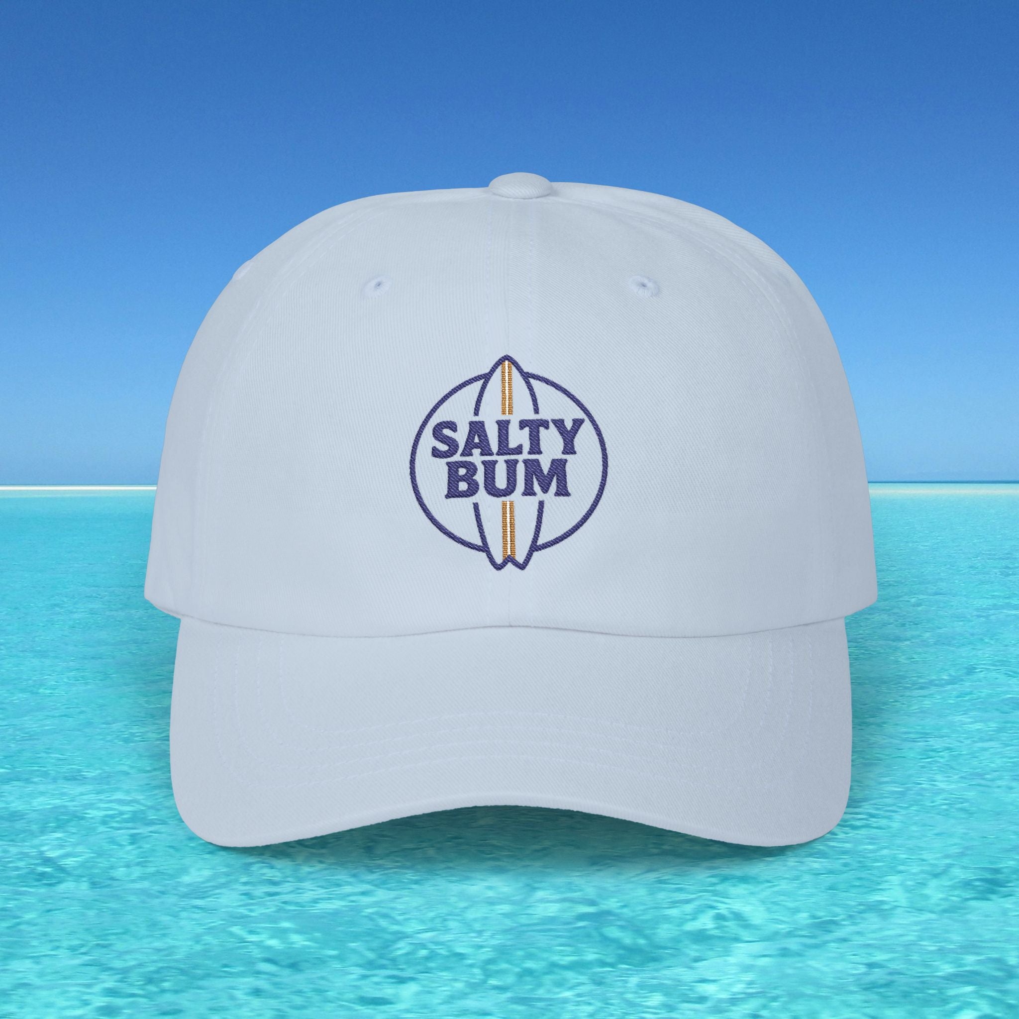White cap with 'Salty Bum' logo on a blue water and sky background