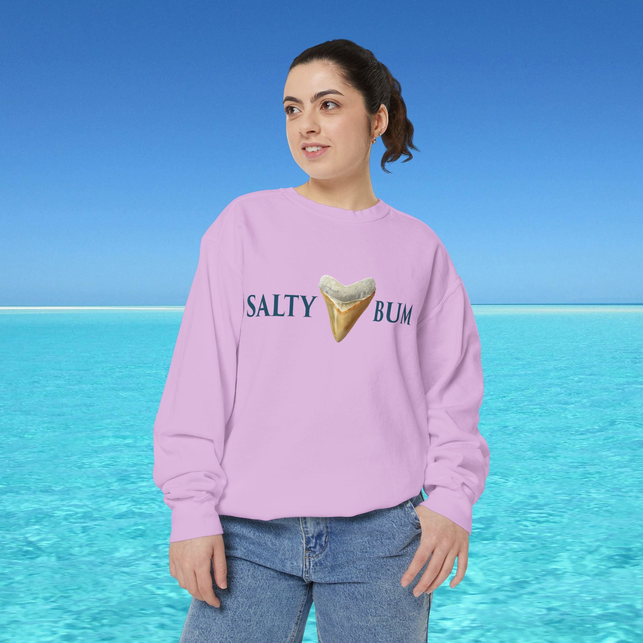 Person wearing a pink sweatshirt with 'Salty Bum' text and ice cream graphic against a blue ocean background