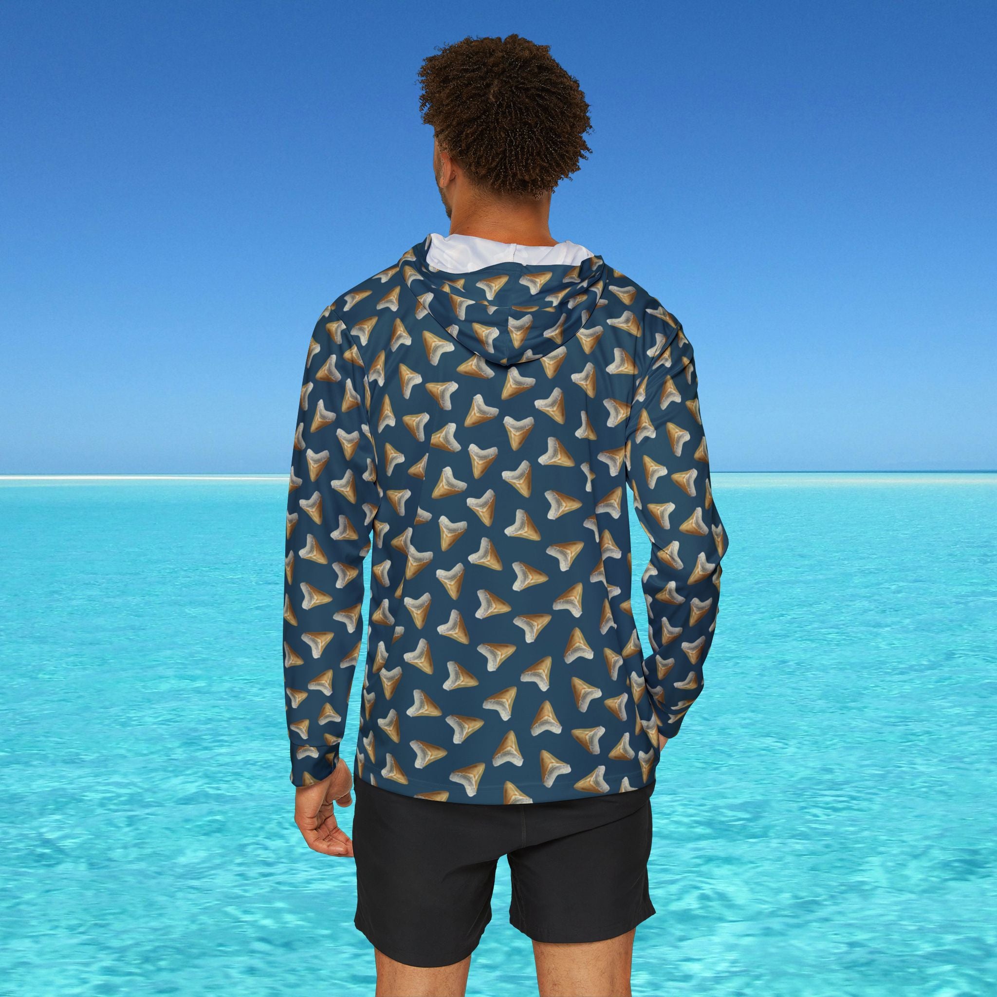 Person wearing a patterned jacket standing in front of a clear blue ocean.