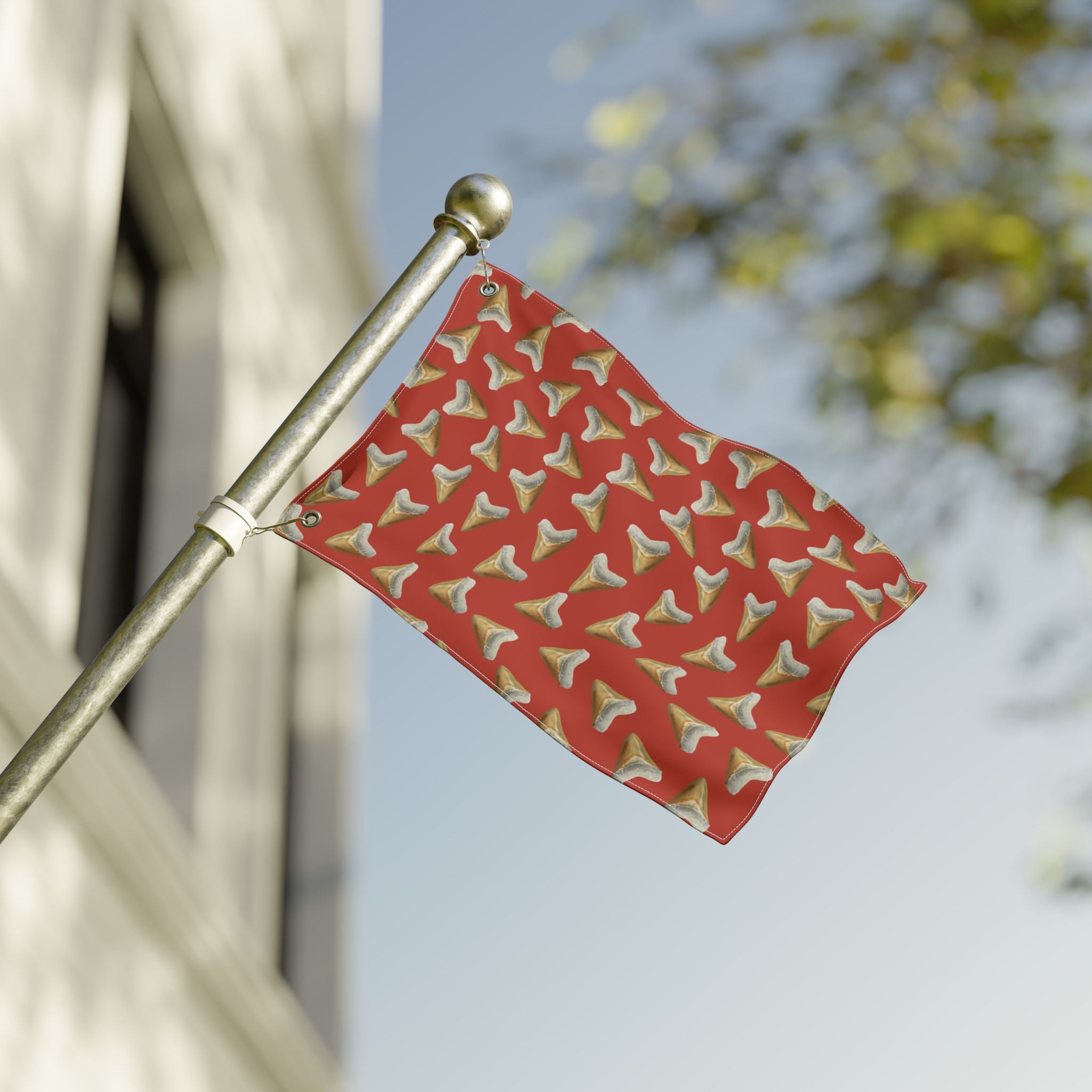 Red flag with gold patterns on a pole against a blurred background