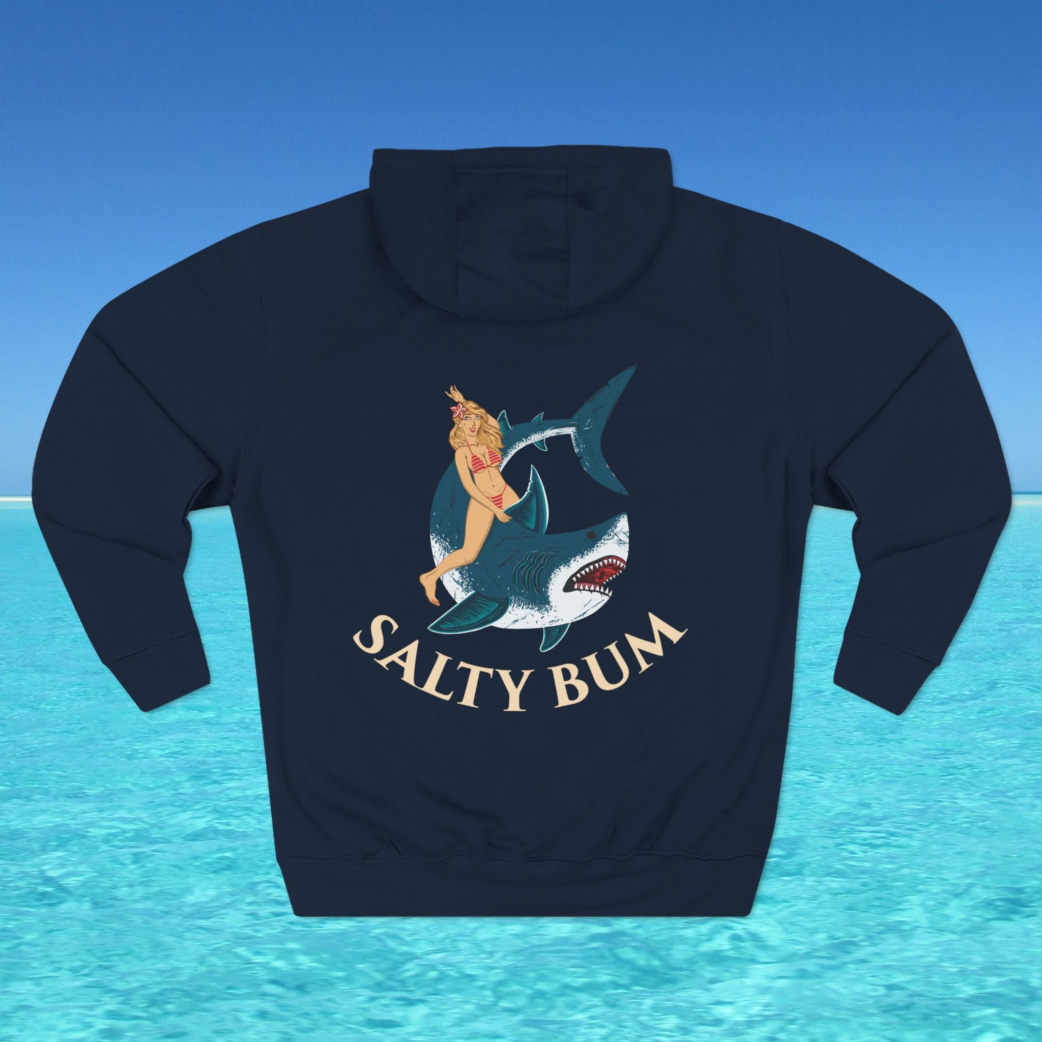 Navy blue hoodie with a graphic of a woman on a shark and 'Salty Bum' text, set against a blue water and sky background.