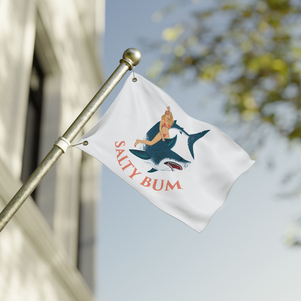Flag with 'Salty Bum' design featuring a person on a shark, against a blurred background.