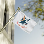 Flag with 'Salty Bum' design featuring a person on a shark, against a blurred background.