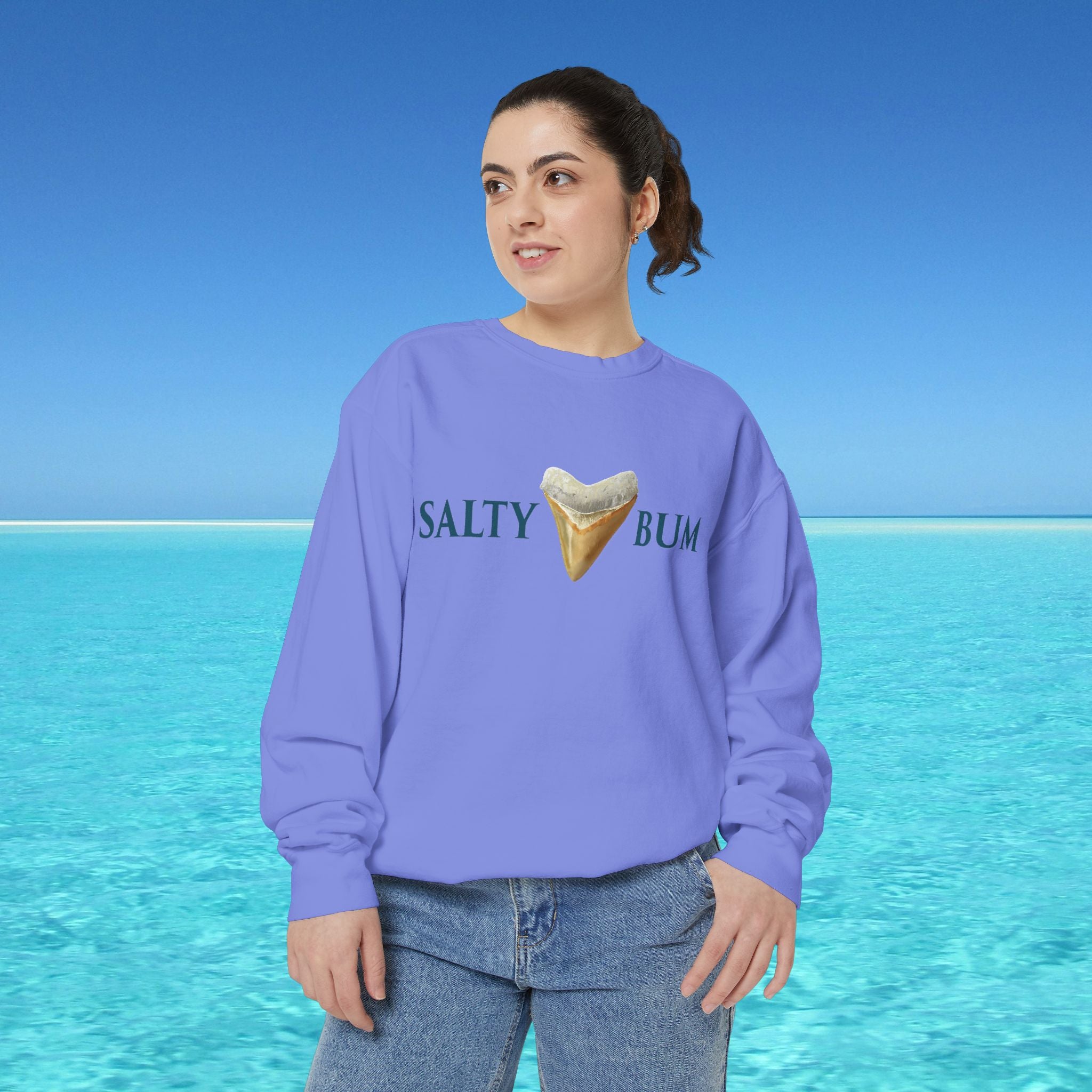 Person wearing a purple sweatshirt with 'Salty Bum' text and ice cream graphic against a blue ocean background