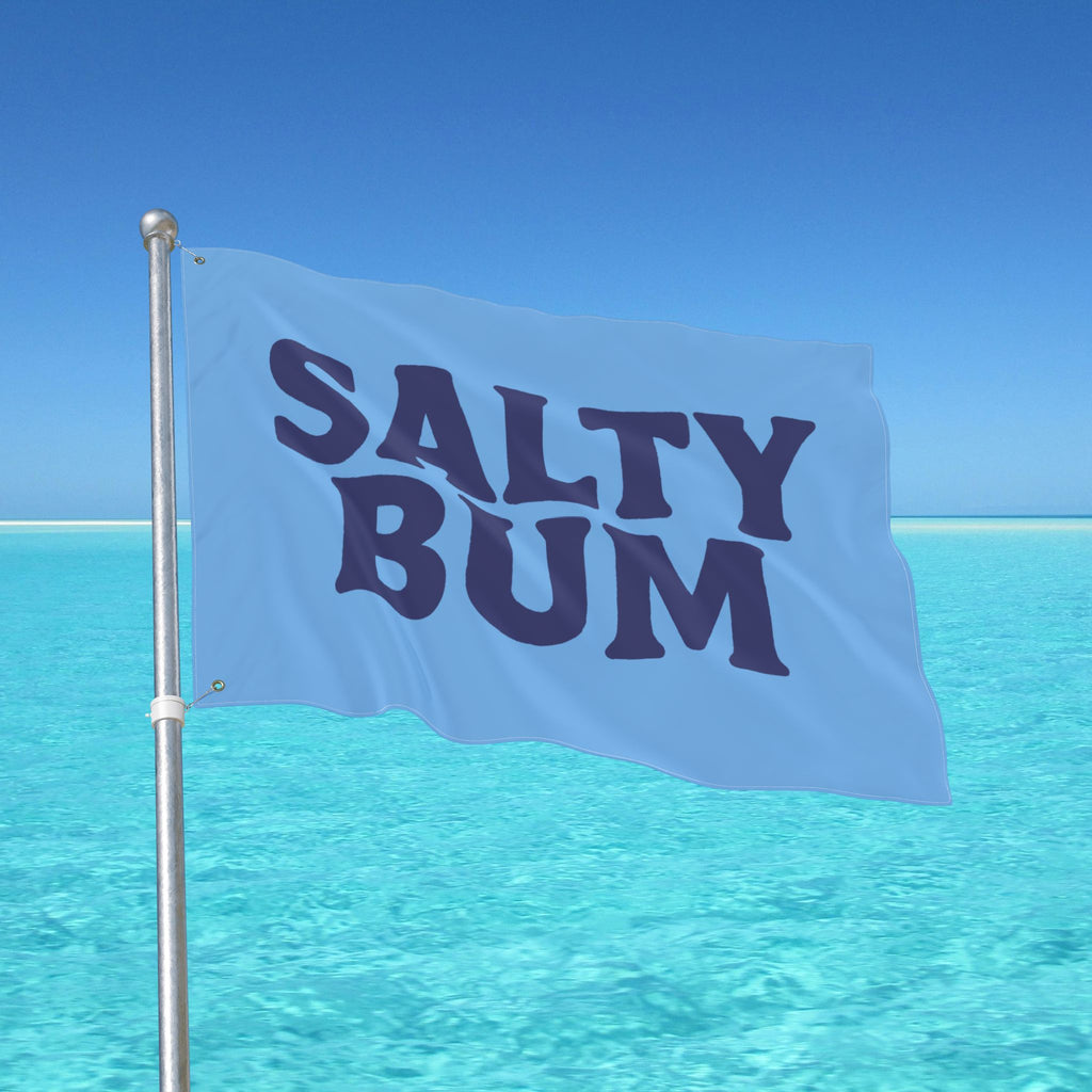 Flag with 'Salty Bum' text against a clear blue sky and ocean.