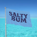 Flag with 'Salty Bum' text against a clear blue sky and ocean.