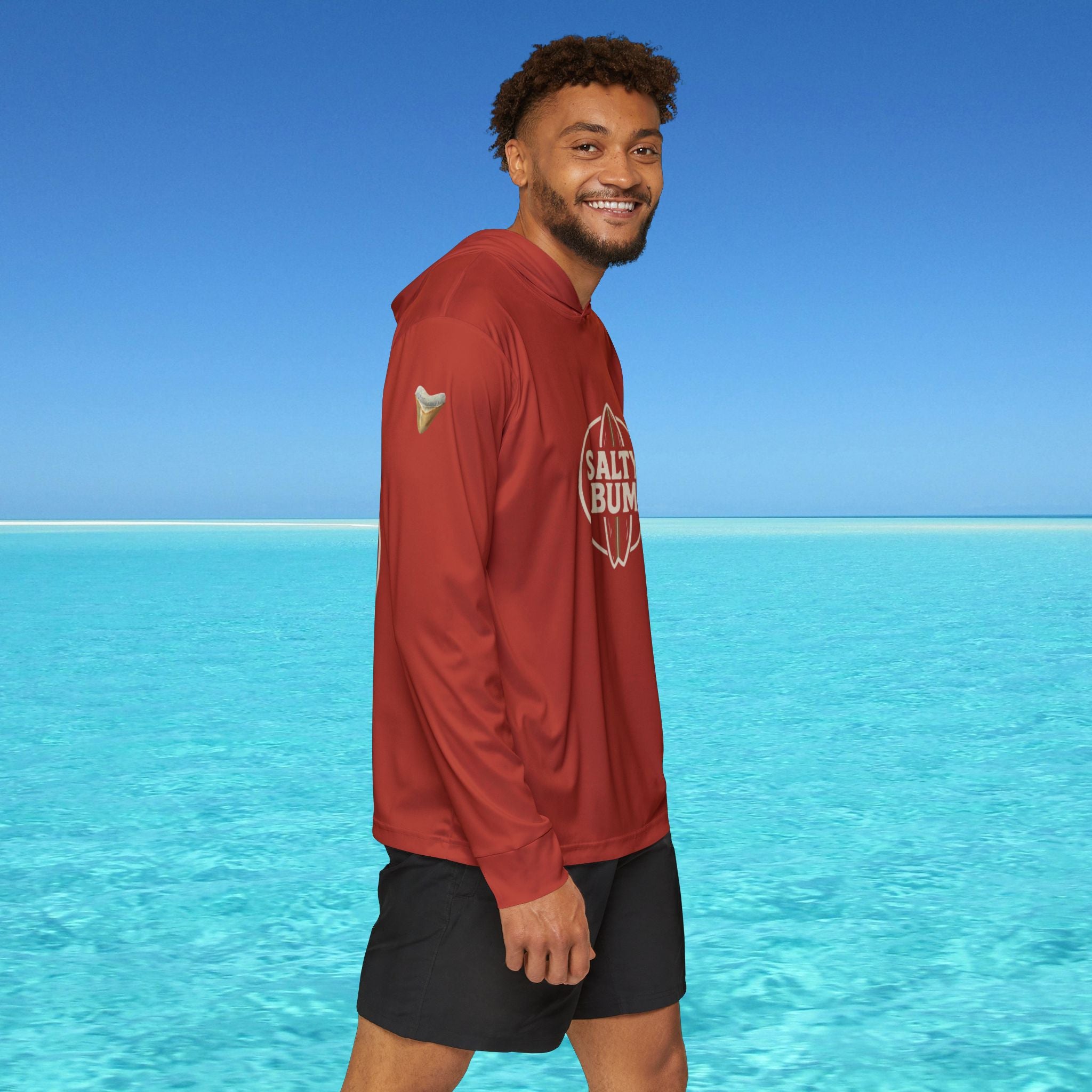 Man wearing a red hoodie with 'Salt Bae' logo standing in clear blue water.