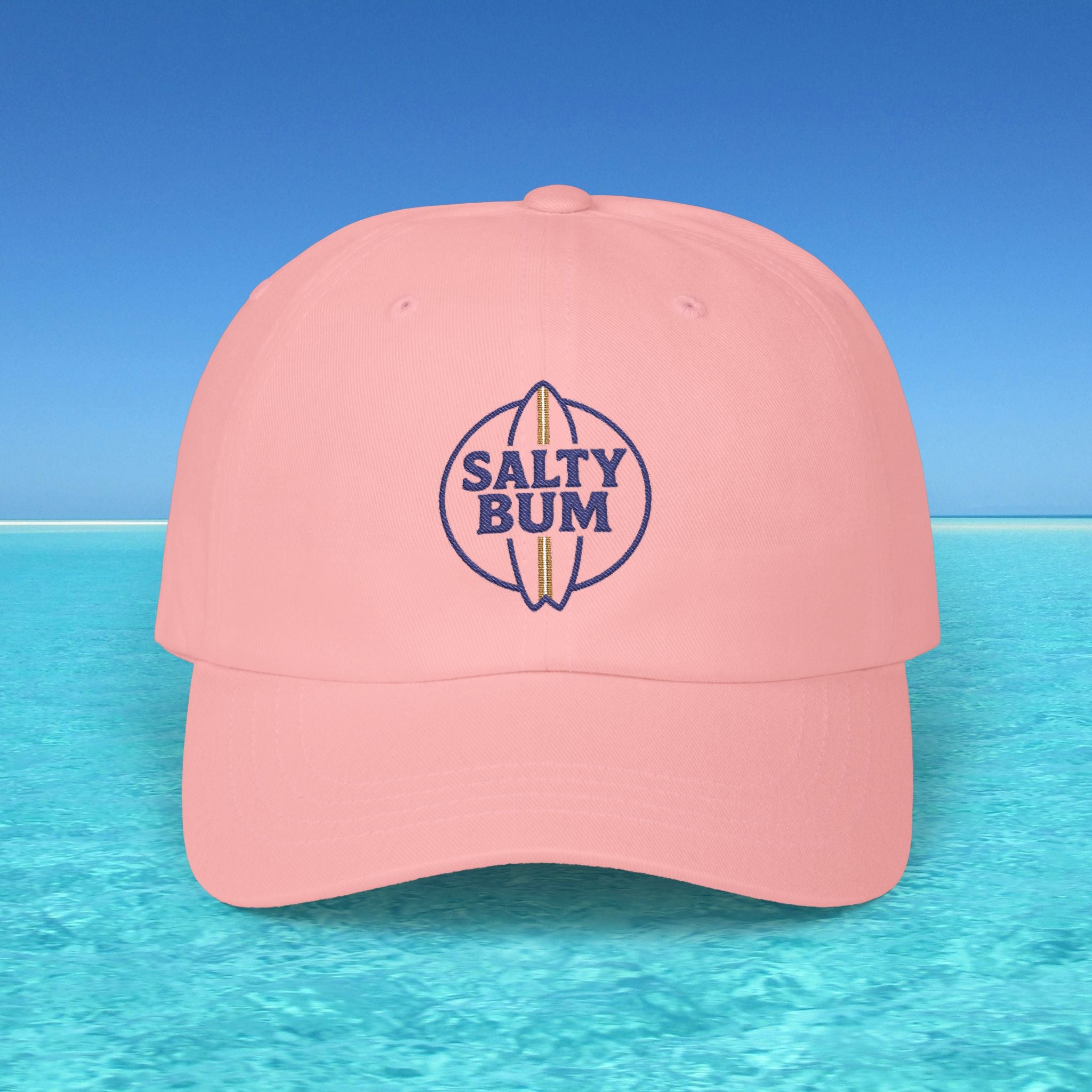 Pink cap with 'Salty Bum' logo on a blue water and sky background