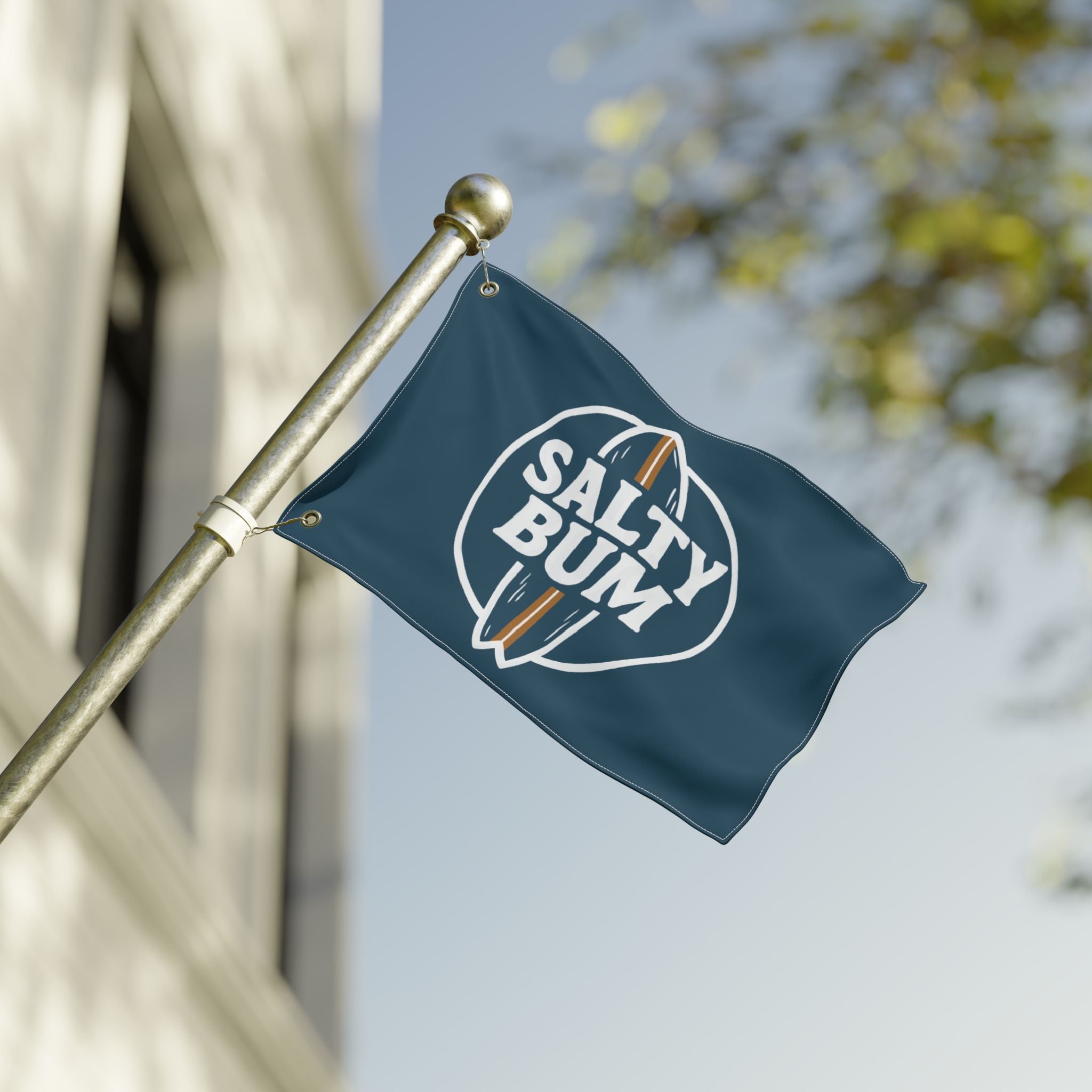 Navy blue flag with 'Salty Bum' logo on a pole against a blurred background
