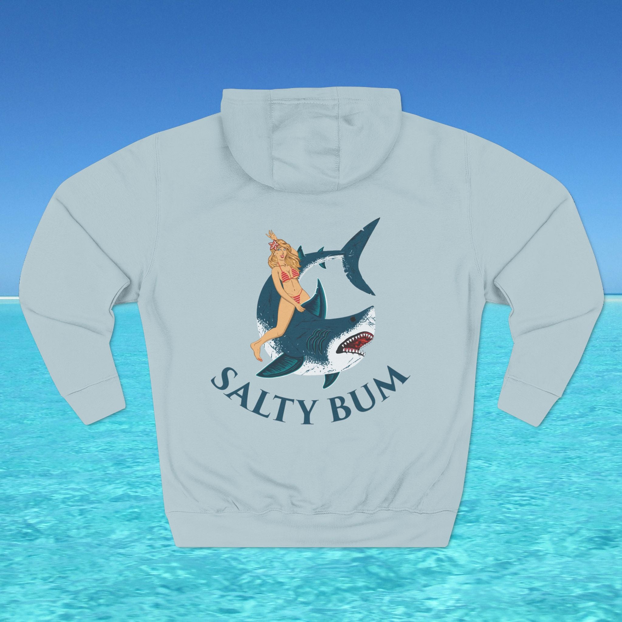 Light gray hoodie with a graphic of a woman on a shark and 'Salty Bum' text, against a blue water and sky background.