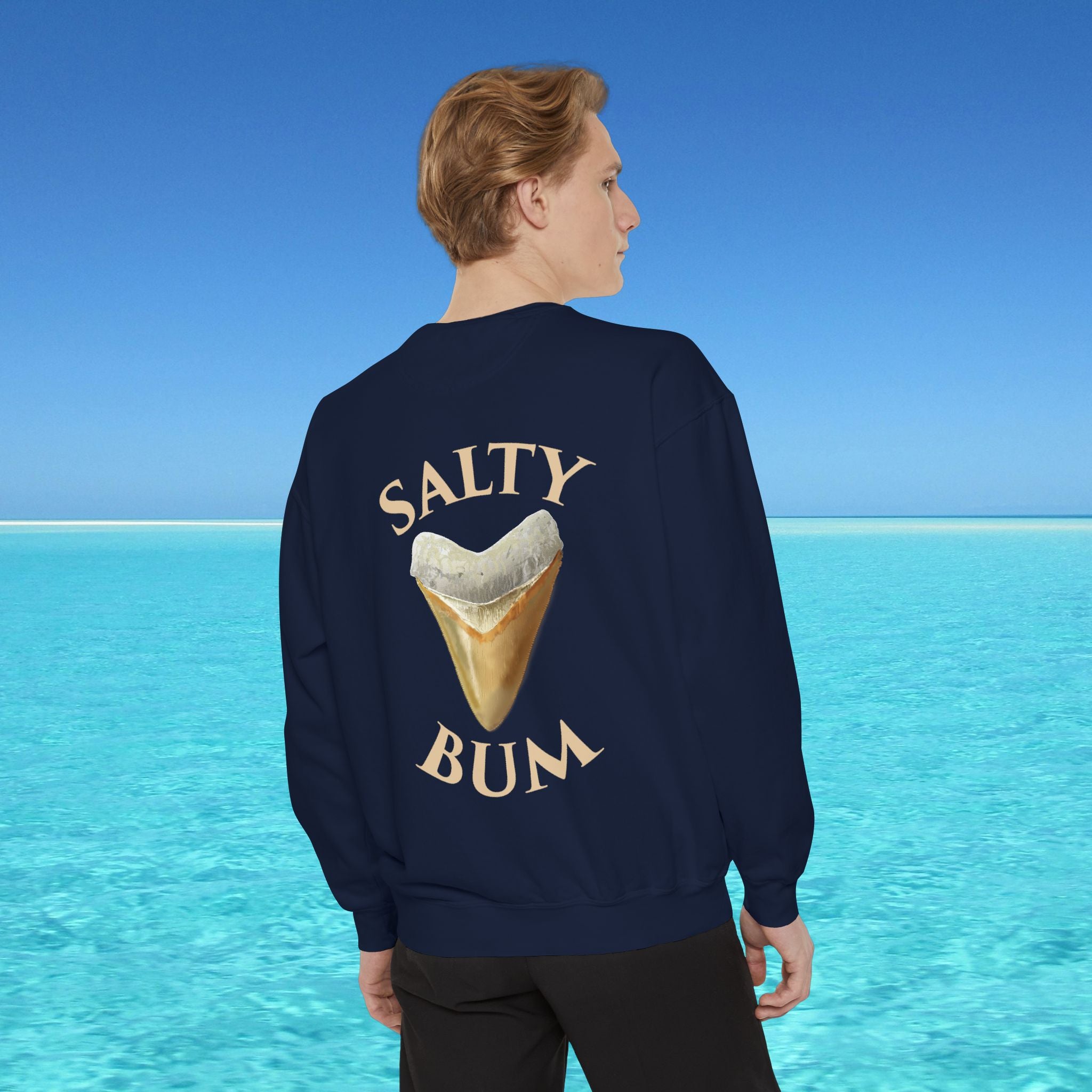 Person wearing a navy sweatshirt with 'Salty Bum' text and ice cream graphic, standing in front of a blue ocean.