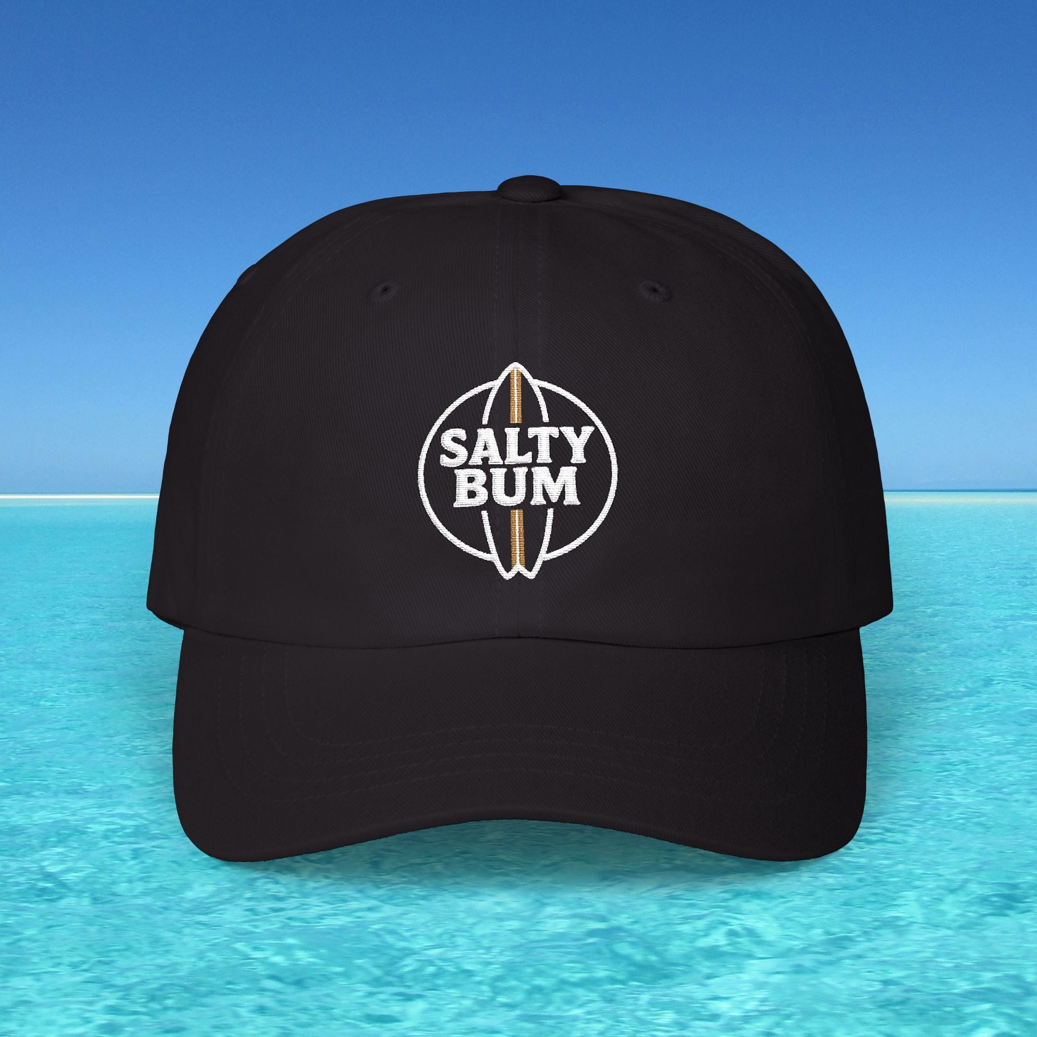 Black cap with 'Salty Bum' logo on a blue water and sky background