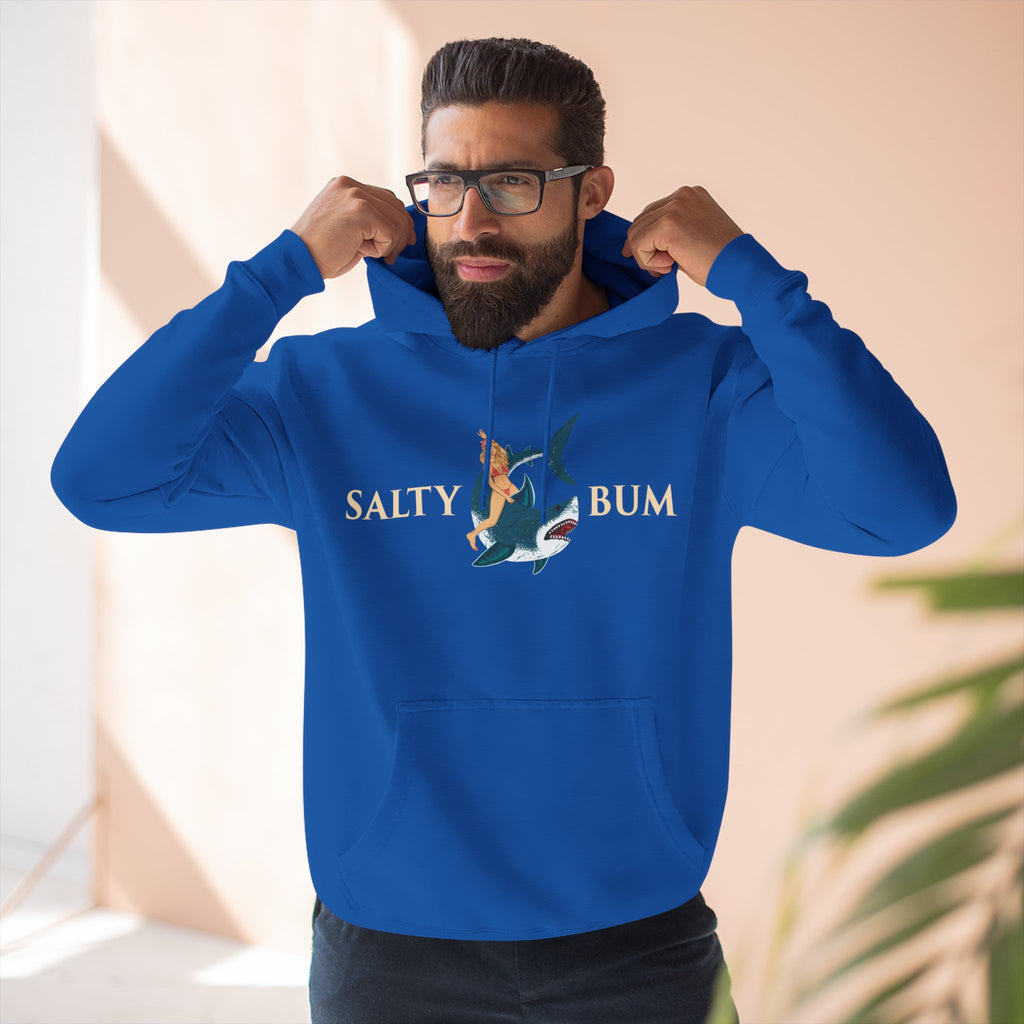 Man wearing a blue hoodie with 'Salty Bum' logo, standing indoors.