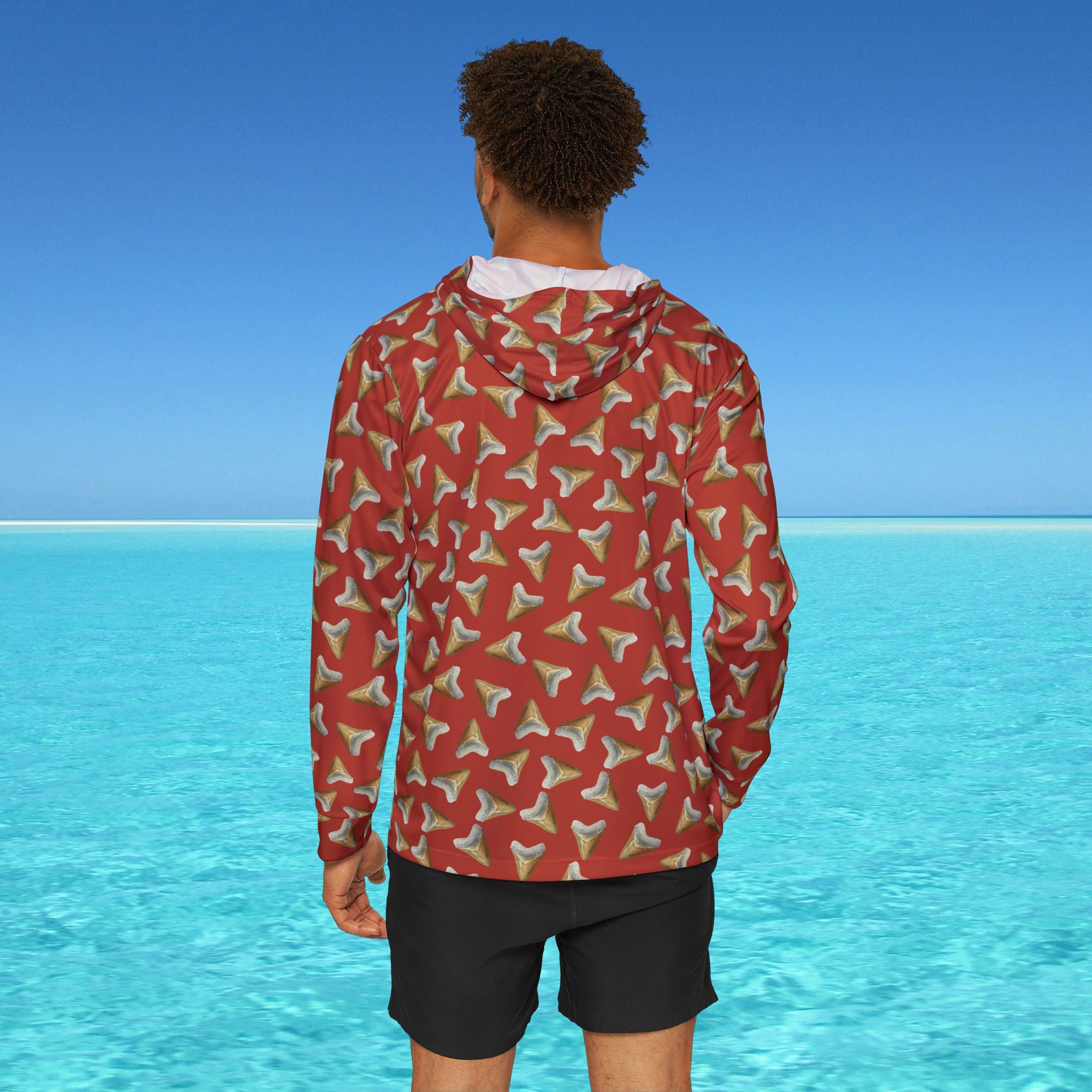 Person wearing a red patterned jacket with a blue ocean and clear sky in the background