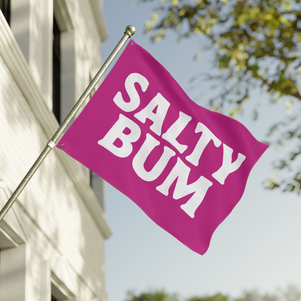 Pink flag with 'Salty Bum' text on a building with trees in the background