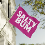Pink flag with 'Salty Bum' text on a building with trees in the background