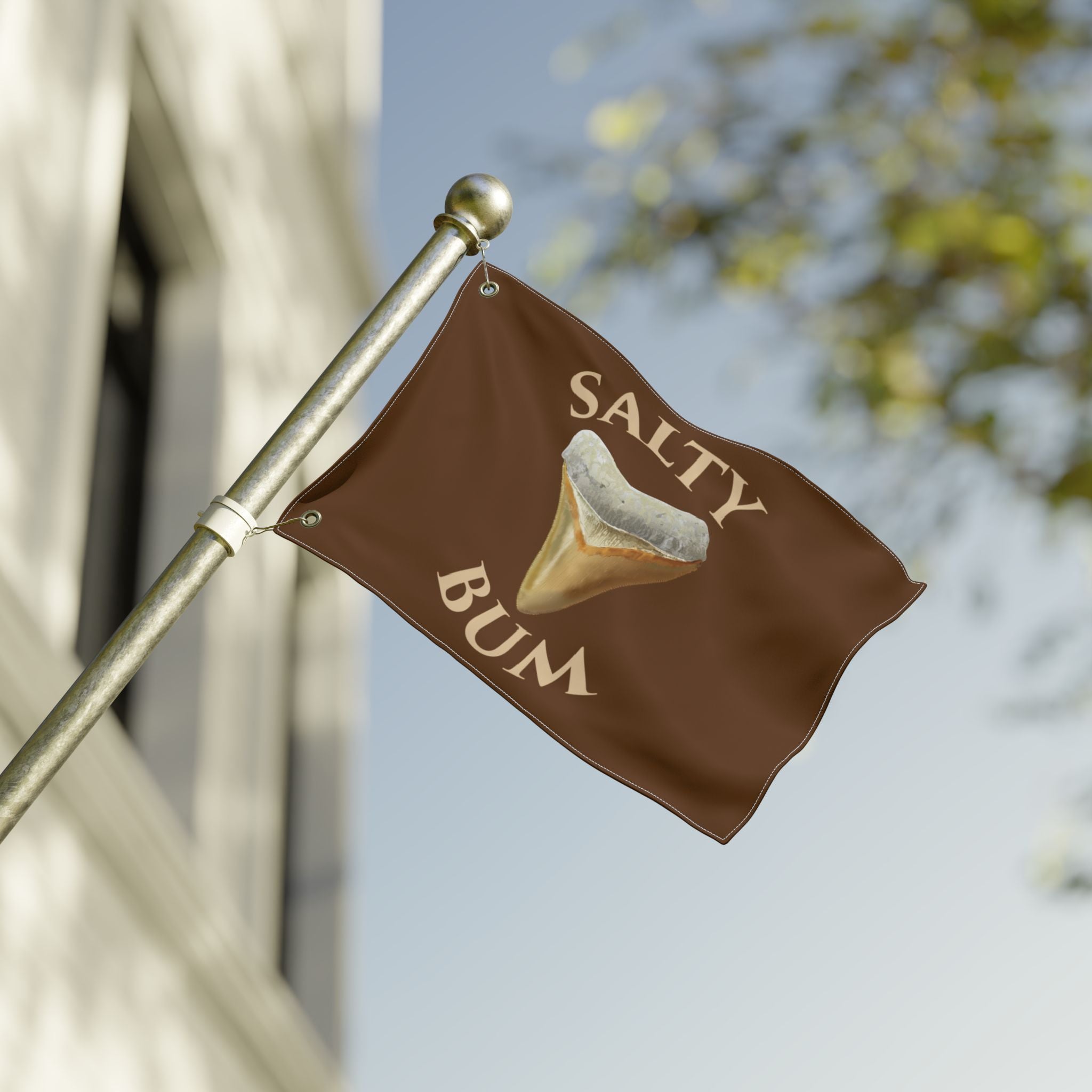Brown flag with 'Salty Bum' text and graphic on a pole against a blurred background