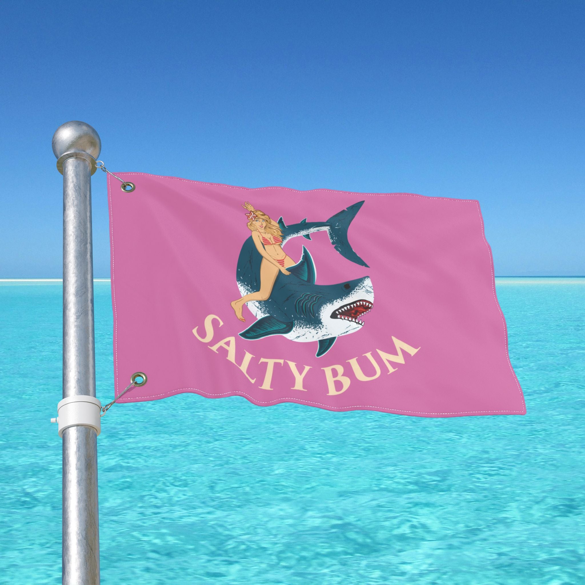 Pink flag with a shark and mermaid design and 'Salty Bum' text, against a clear blue sky.