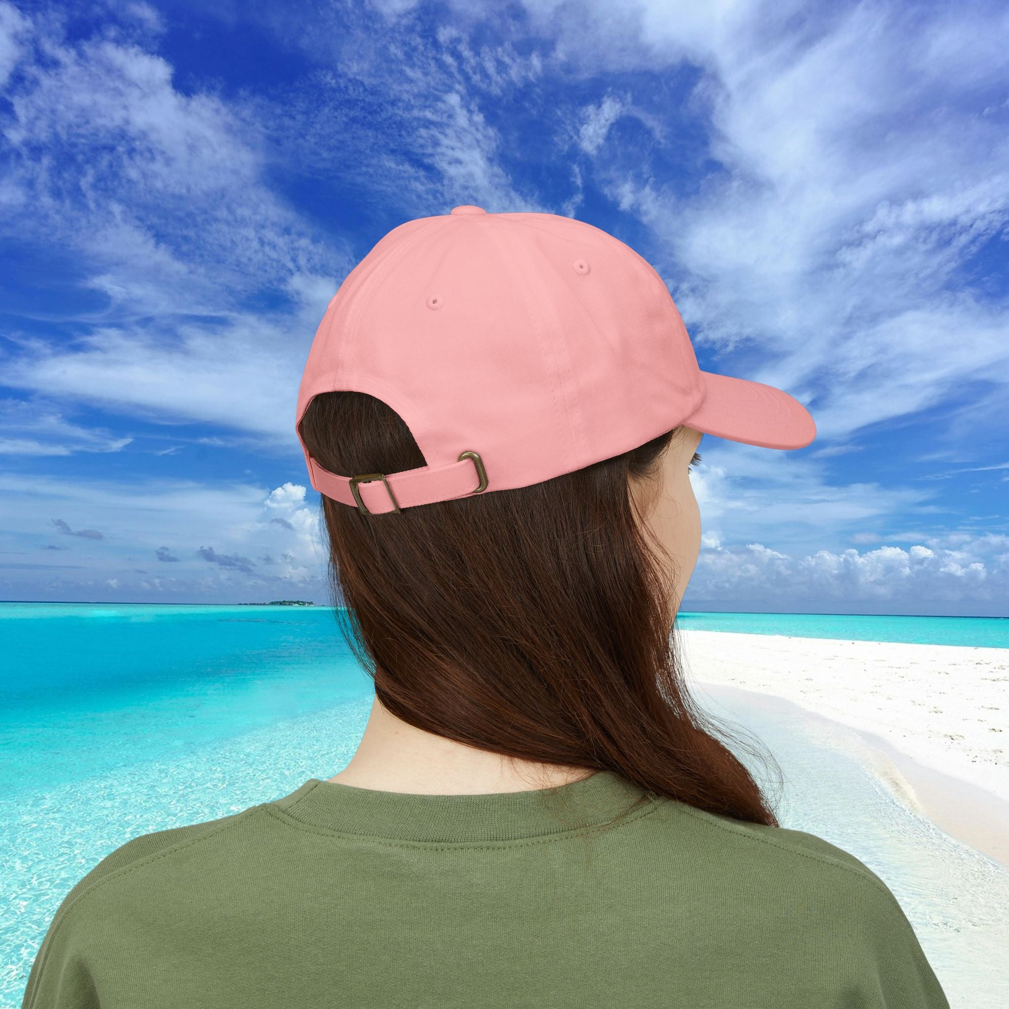 Person wearing a pink cap with a beach and blue sky in the background