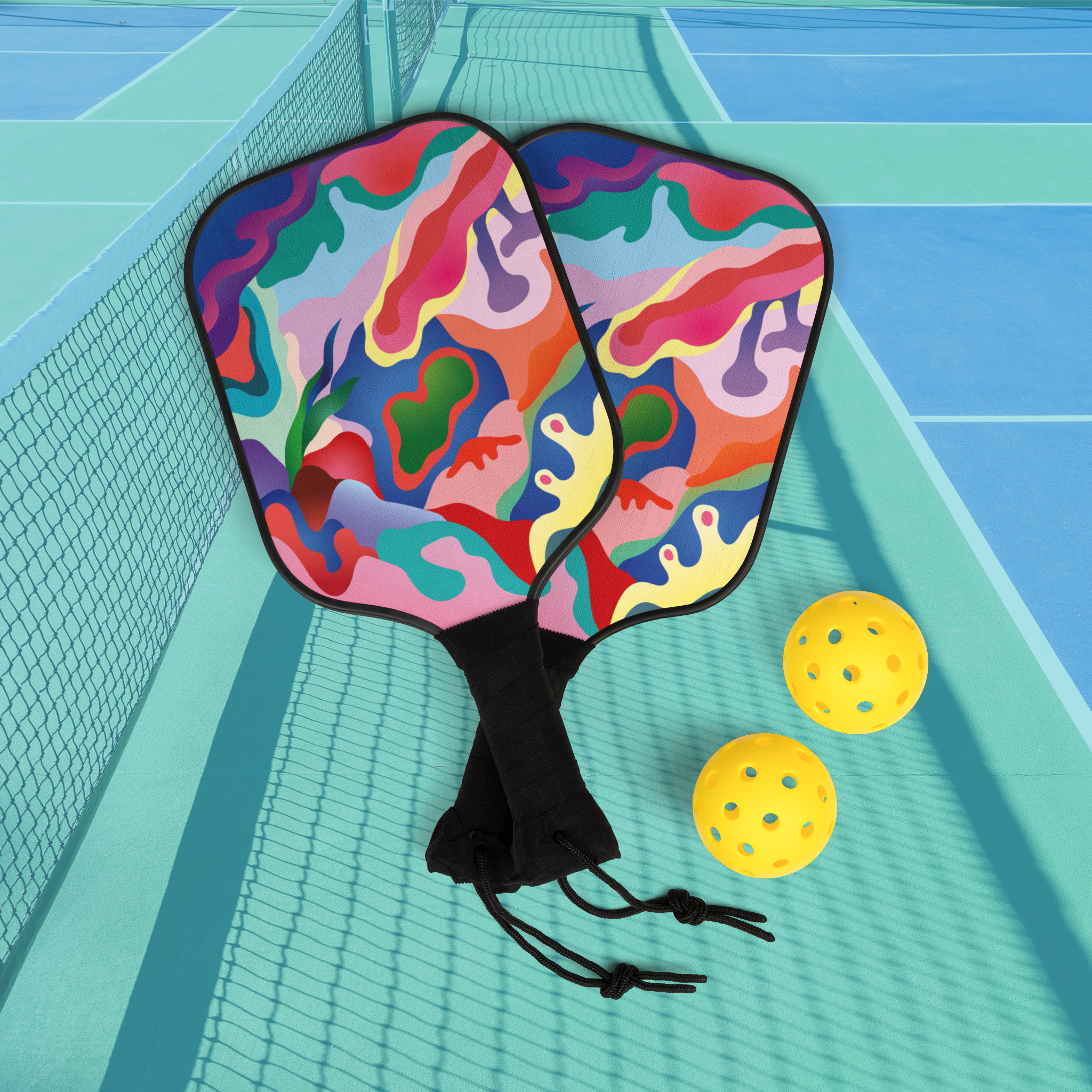 Colorful pickleball paddles with a ball on a court