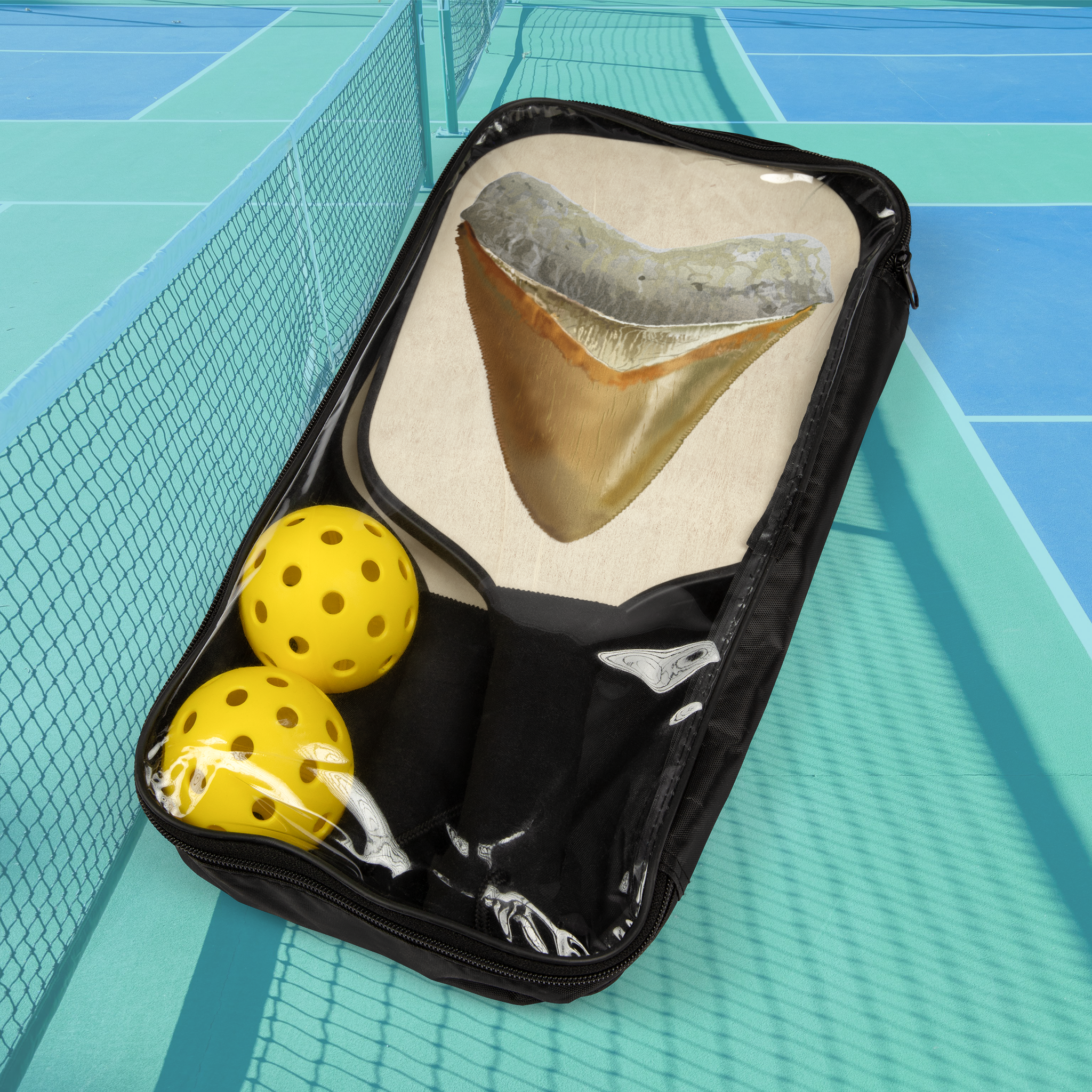 Black bag with a shark tooth model and yellow balls on a blue tennis court background