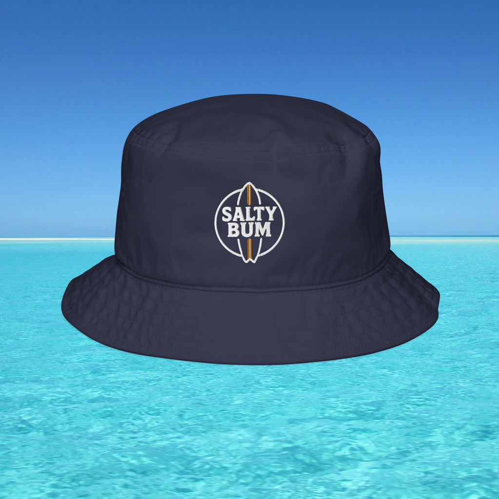 Navy bucket hat with 'Salty Bum' logo on a blue water and sky background