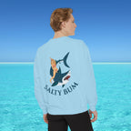 Person wearing a light blue sweatshirt with a shark and bikini graphic and 'Salty Bum' text, standing in front of a blue ocean.