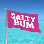 Pink flag with 'Salty Bum' text against a clear blue sky and ocean.